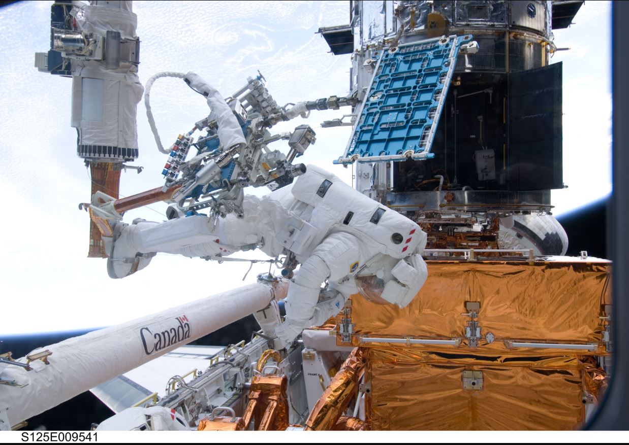 During the mission’s fourth spacewalk, Michael Good and Michael Massimino faced a curious challenge: a stripped screw delayed the removal of a handrail (pictured inside the telescope to the upper right of Good’s helmet in this photo) on the outside of the Space Telescope Imaging Spectrograph (STIS). After nearly four hours of troubleshooting, Good, Massimino, the rest of the crew and a team back on Earth found a way to remove the handrail and continue the mission. - Image Credit: NASA