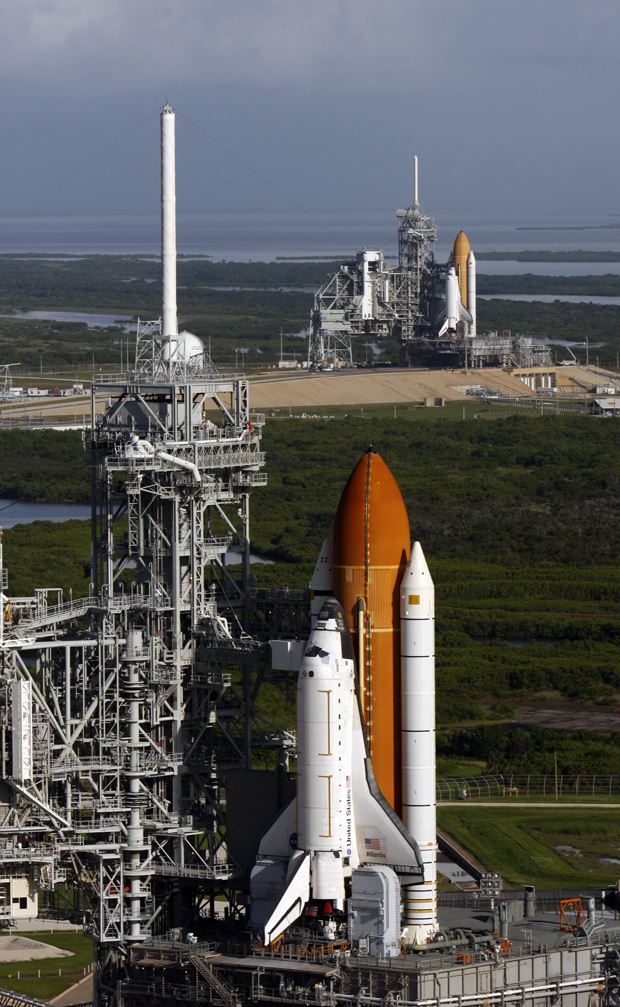 In the foreground, the space shuttle Atlantis stands ready for launch. A backup space shuttle (shown behind Atlantis) was also prepared for launch at NASA’s Kennedy Space Center in Florida, in the event that the STS-125 crew experienced an emergency…