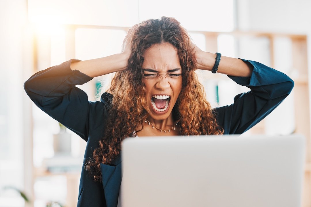 Frustrated woman in front of her computer which has been hacked