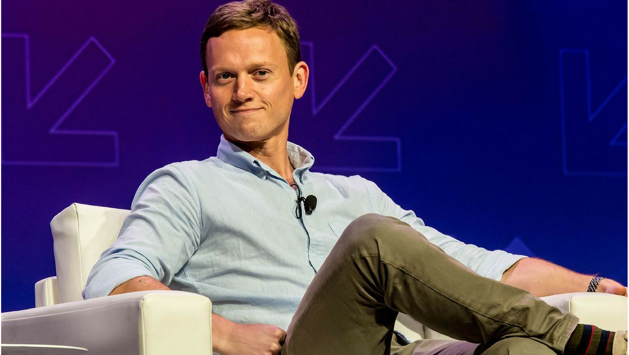 Vietor, do Pod Save America, acha devemos pagar por bom jornalismo online. (Descrição da imagem: Ex-porta-voz do governo Obama está sentado em uma poltrona e sorri enquanto apresenta seu podcast)