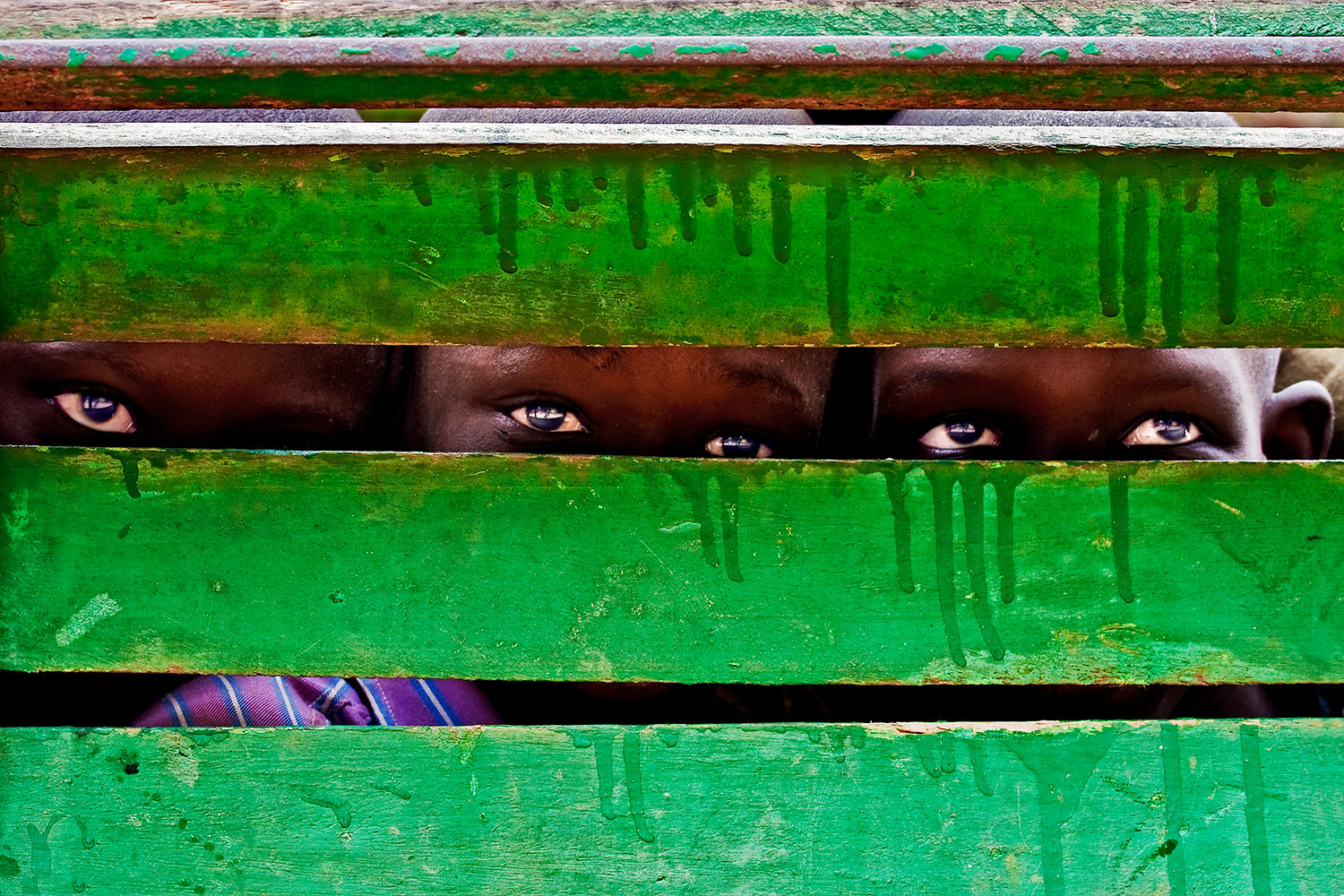 Three children playing behind a bench. Senegal-Isla of Goreè.