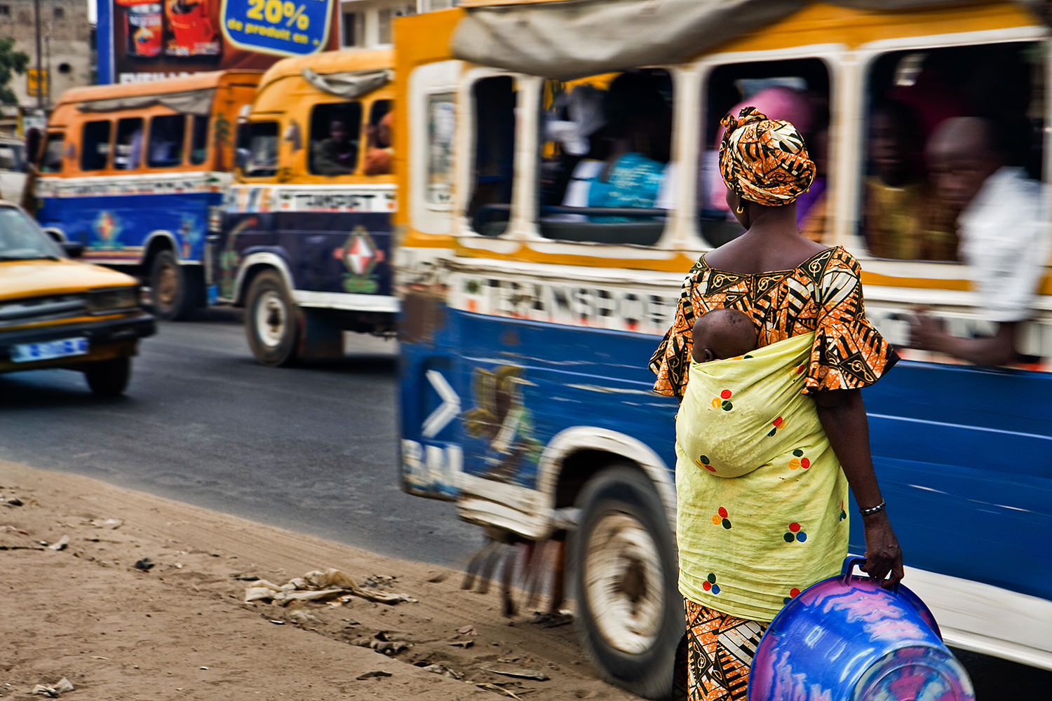 A woman with a child waits in the Dakar traffic. Senegal