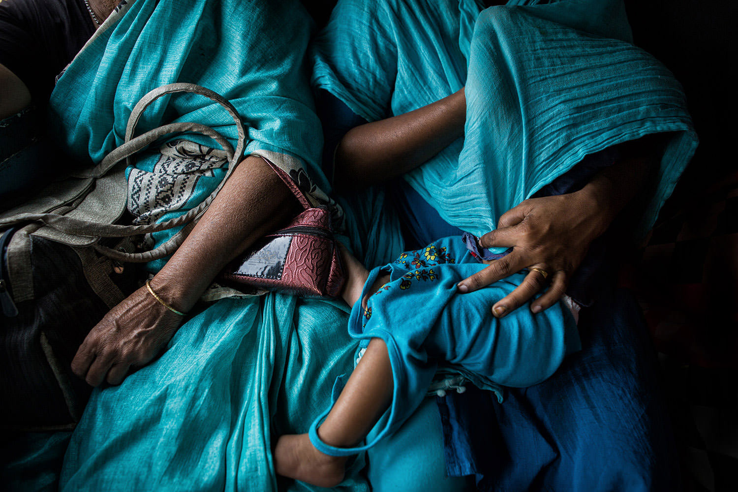 A child is fed by the mother and covered with a sari on an Indian Train