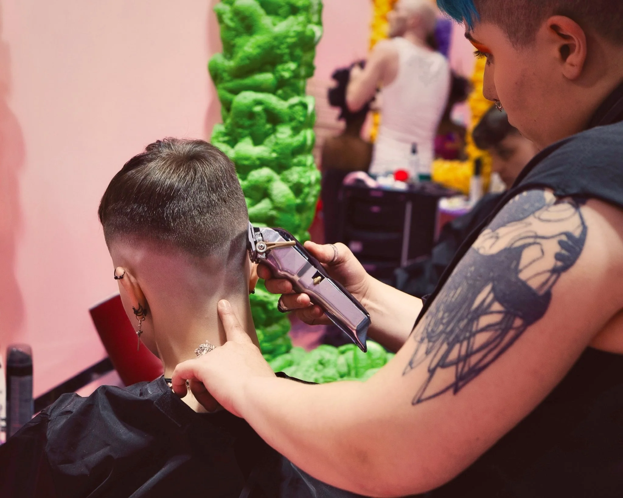 Barber Below barber using clippers to create a short faded haircut