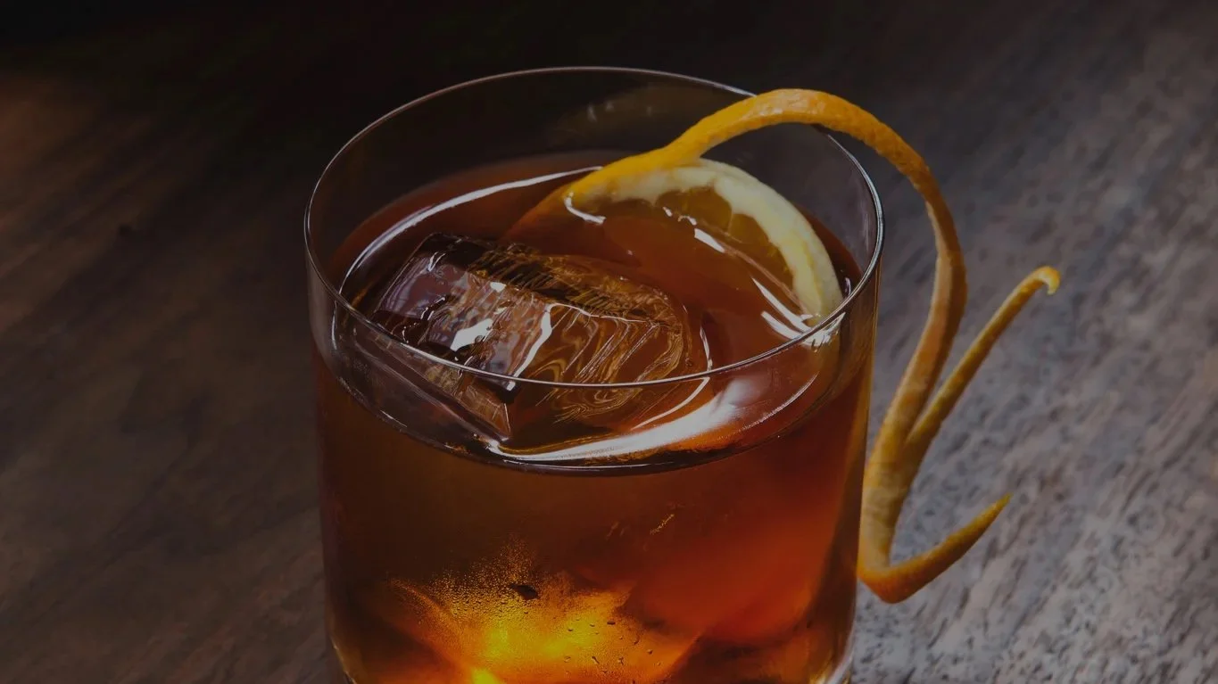 A glass of iced tea with a lemon wedge and a lemon twist garnish.