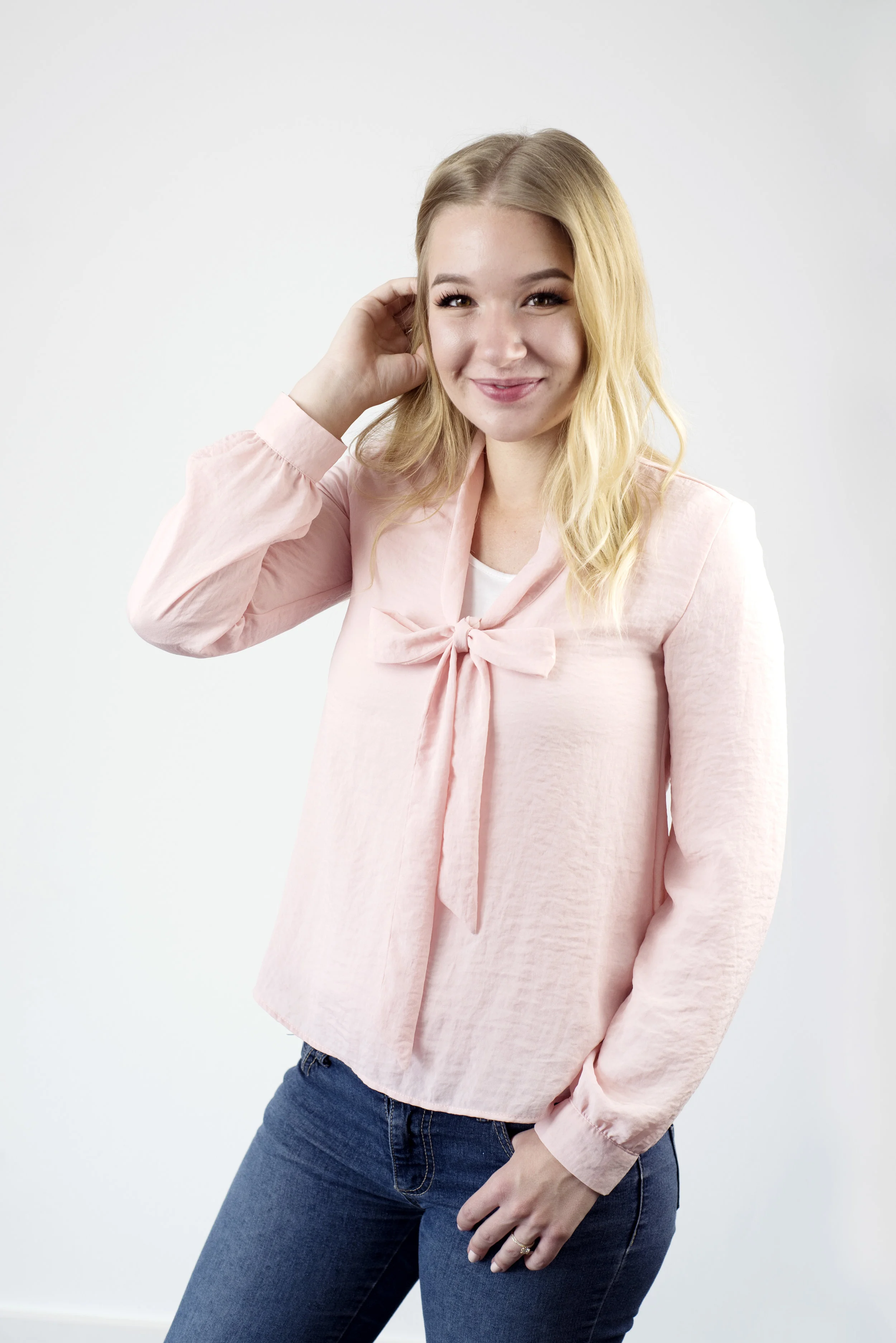 Woman smiles into the camera, now with her shirt bow staying in place