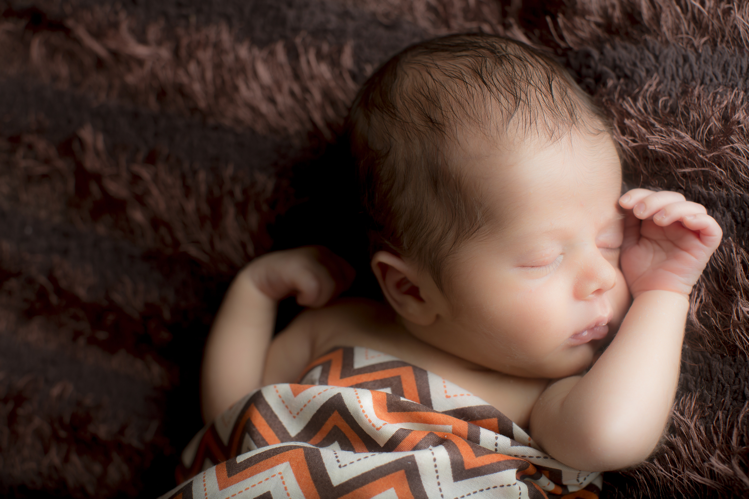 11 modern newborn boy swaddled in chevron posed hands studio session.jpg