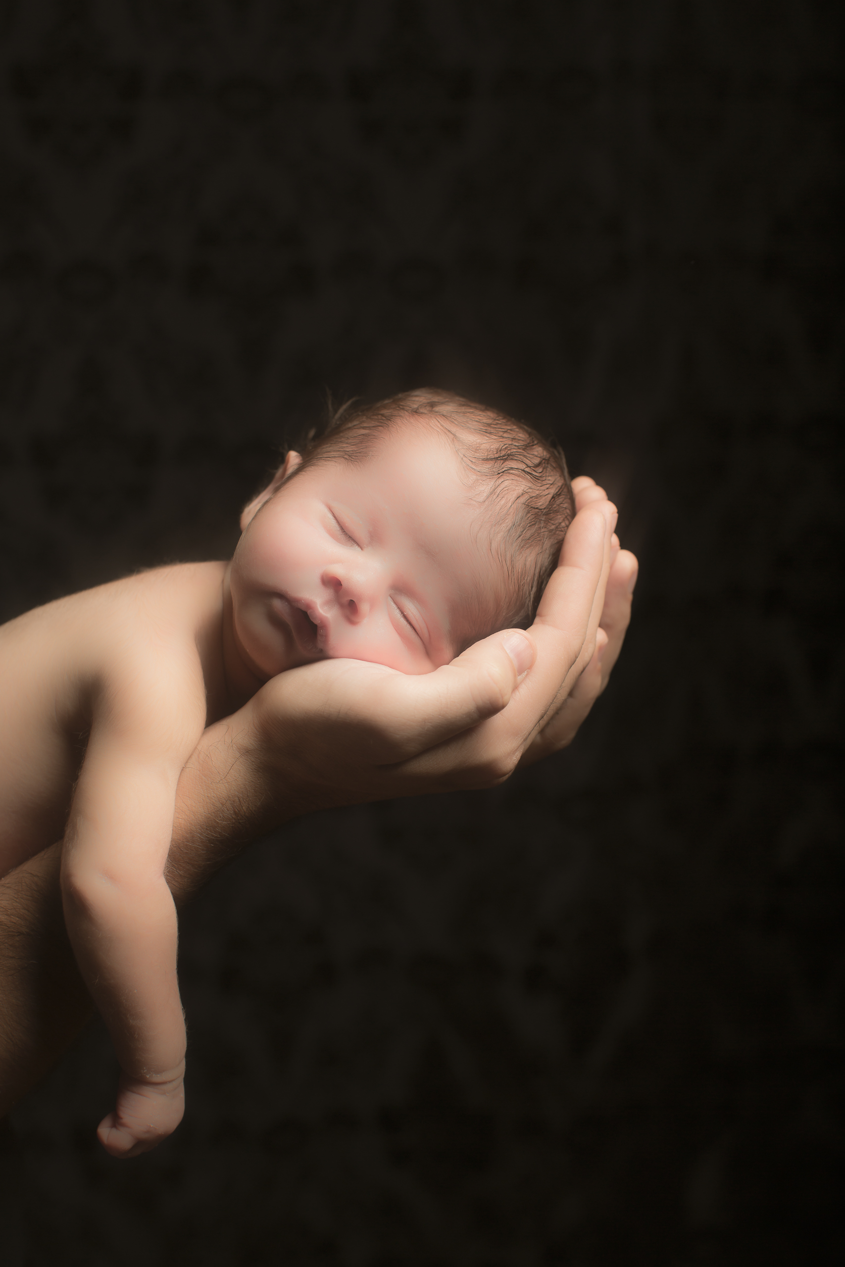 47 modern fathers hands cradling son newborn photography on black studio session.jpg