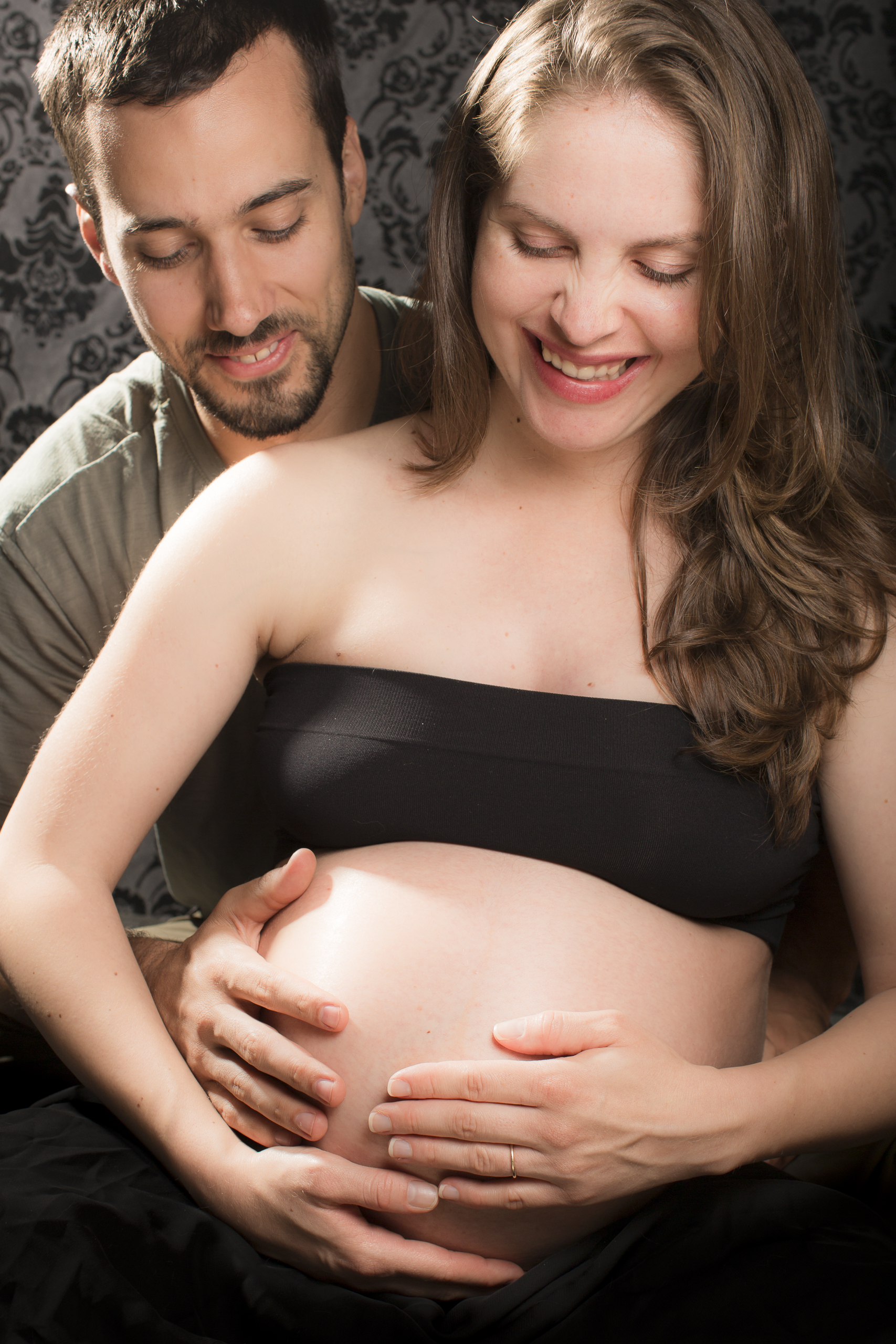 45 modern maternity photography studio session mom and dad feeling baby hands on belly laughing.jpg