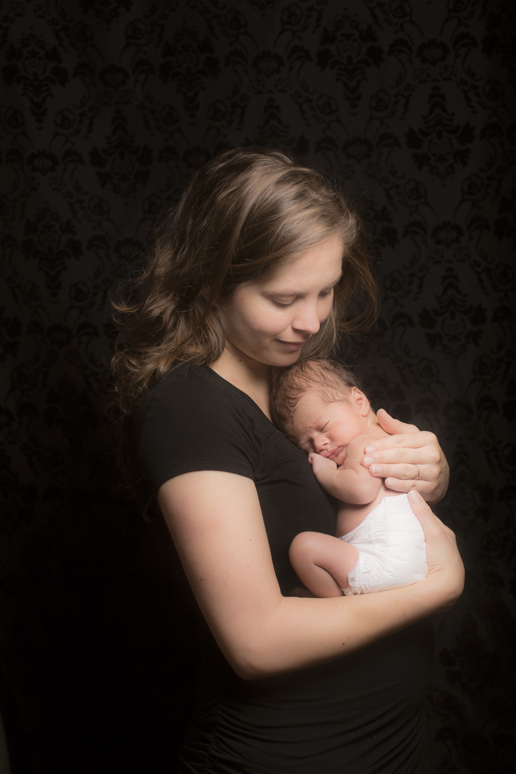 49 modern mother cradling son newborn photography on black studio session.jpg