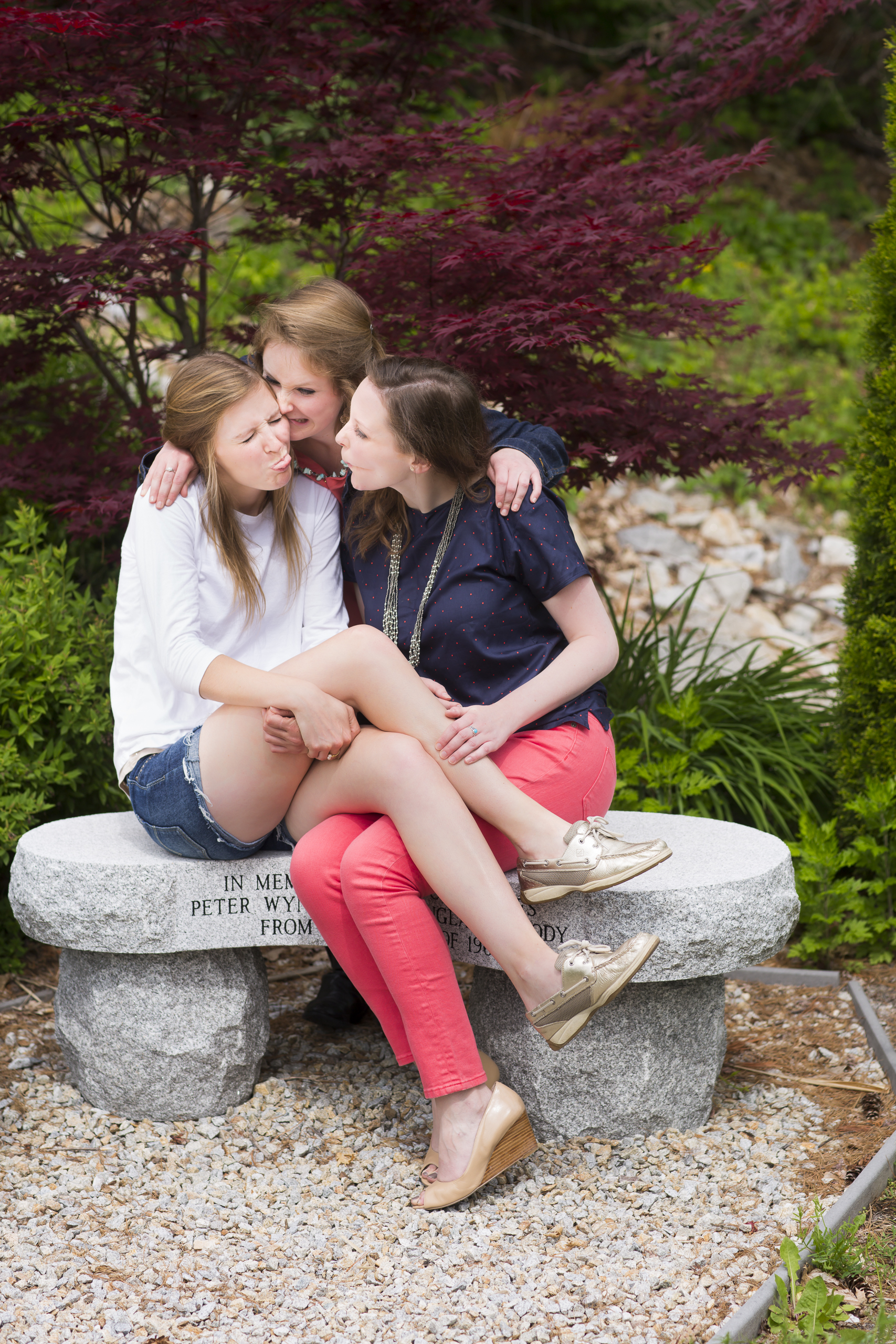 32 3 sisters family portrait outdoor session being silly on stone bench with red maple tree.jpg