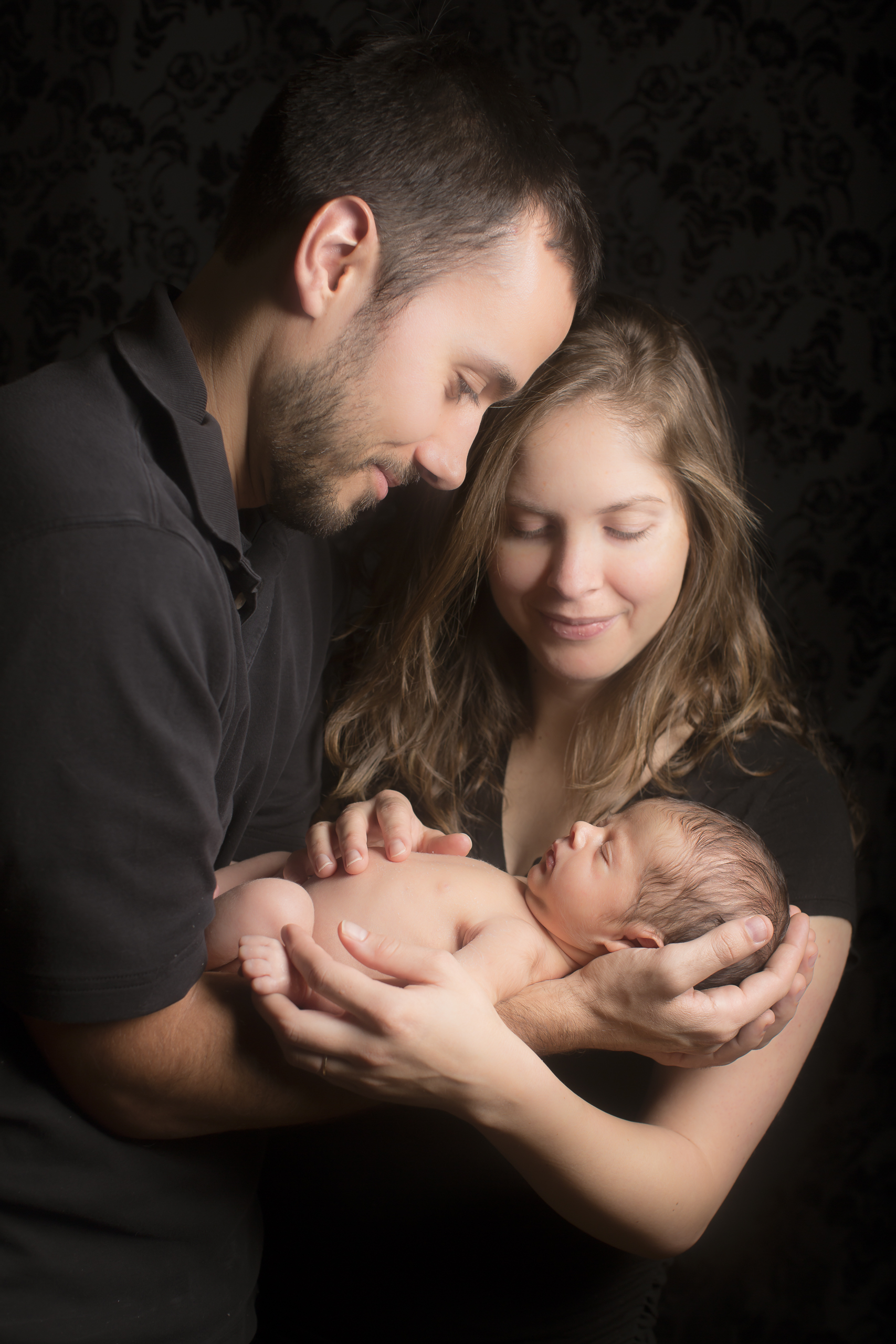 46 modern father and mother cradling newborn photography on black studio session.jpg