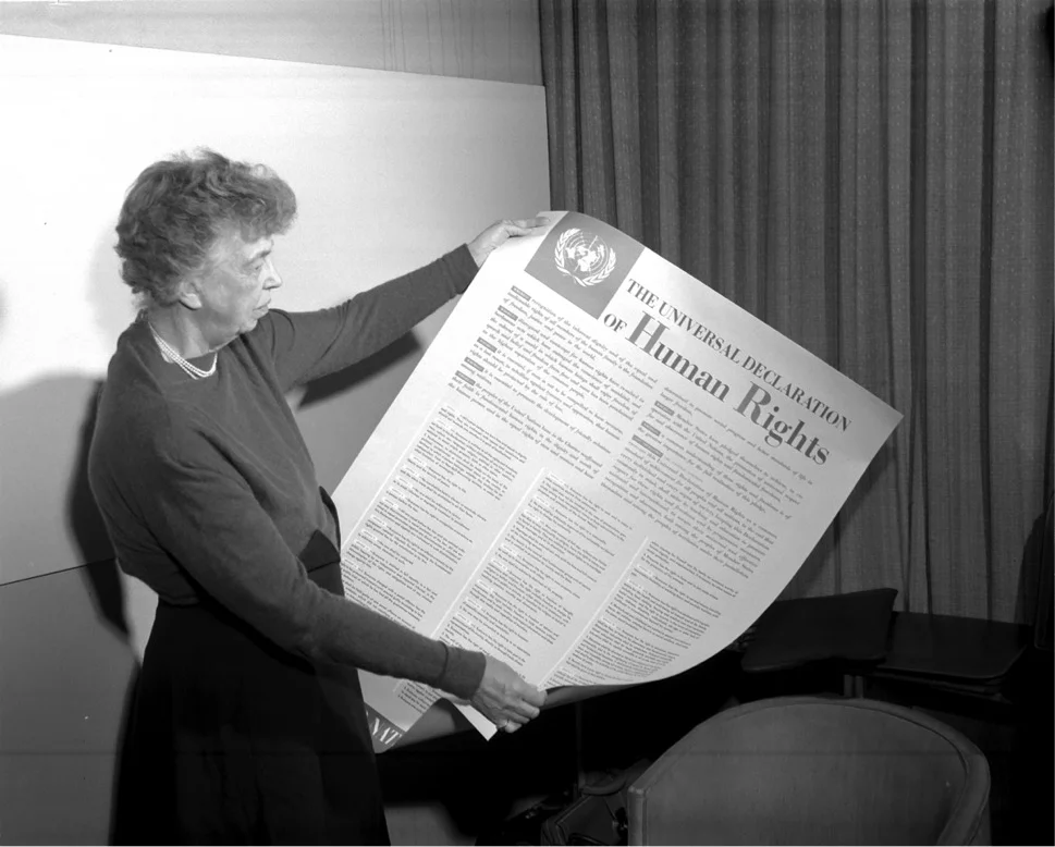Eleanor Roosevelt holds a copy of the UDHR.