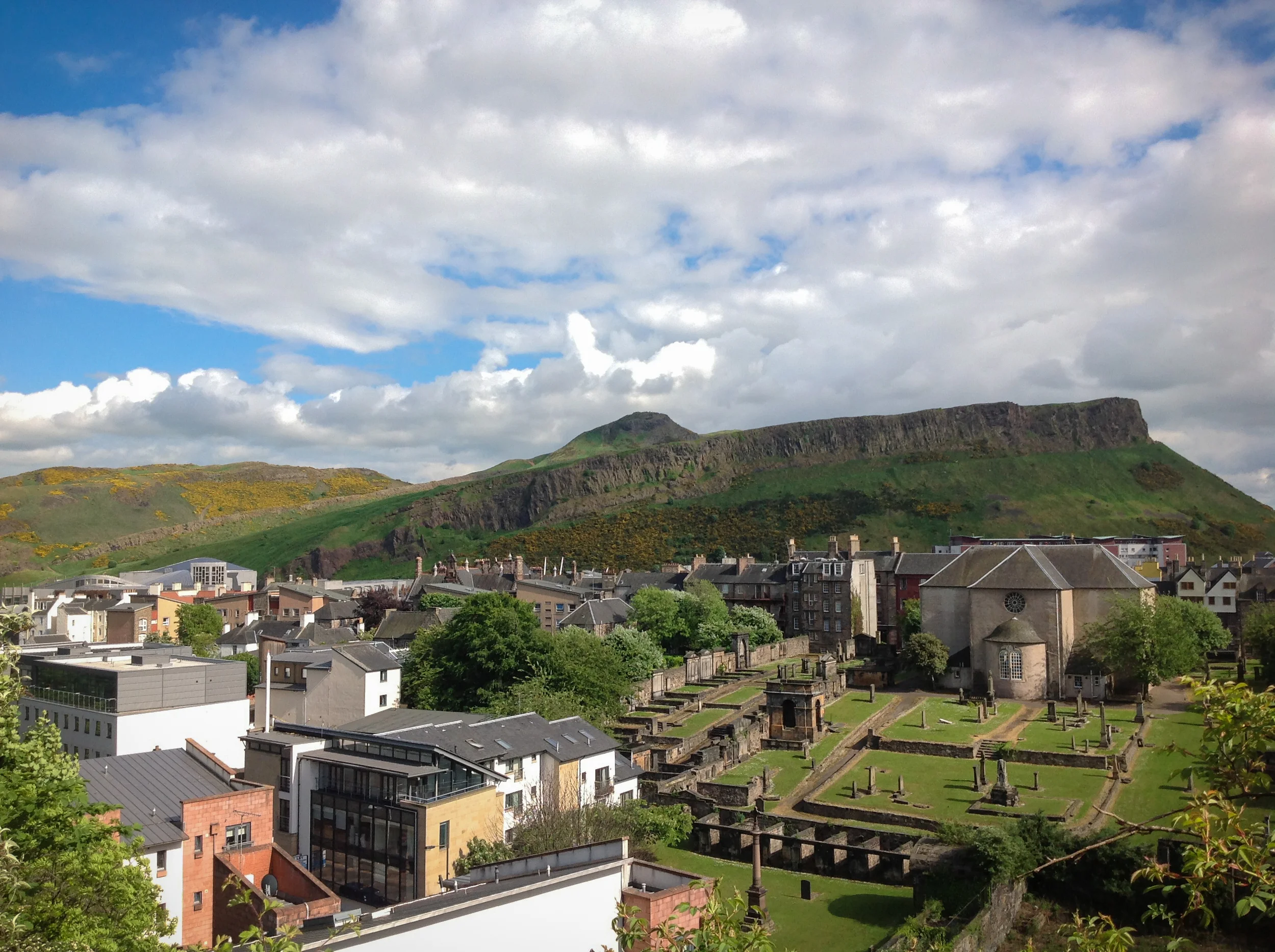 Arthur's Seat, Canongate Kirk and its yard, and the chimneys of THE ROYAL MILE viewed from the south slope of Calton Hill.