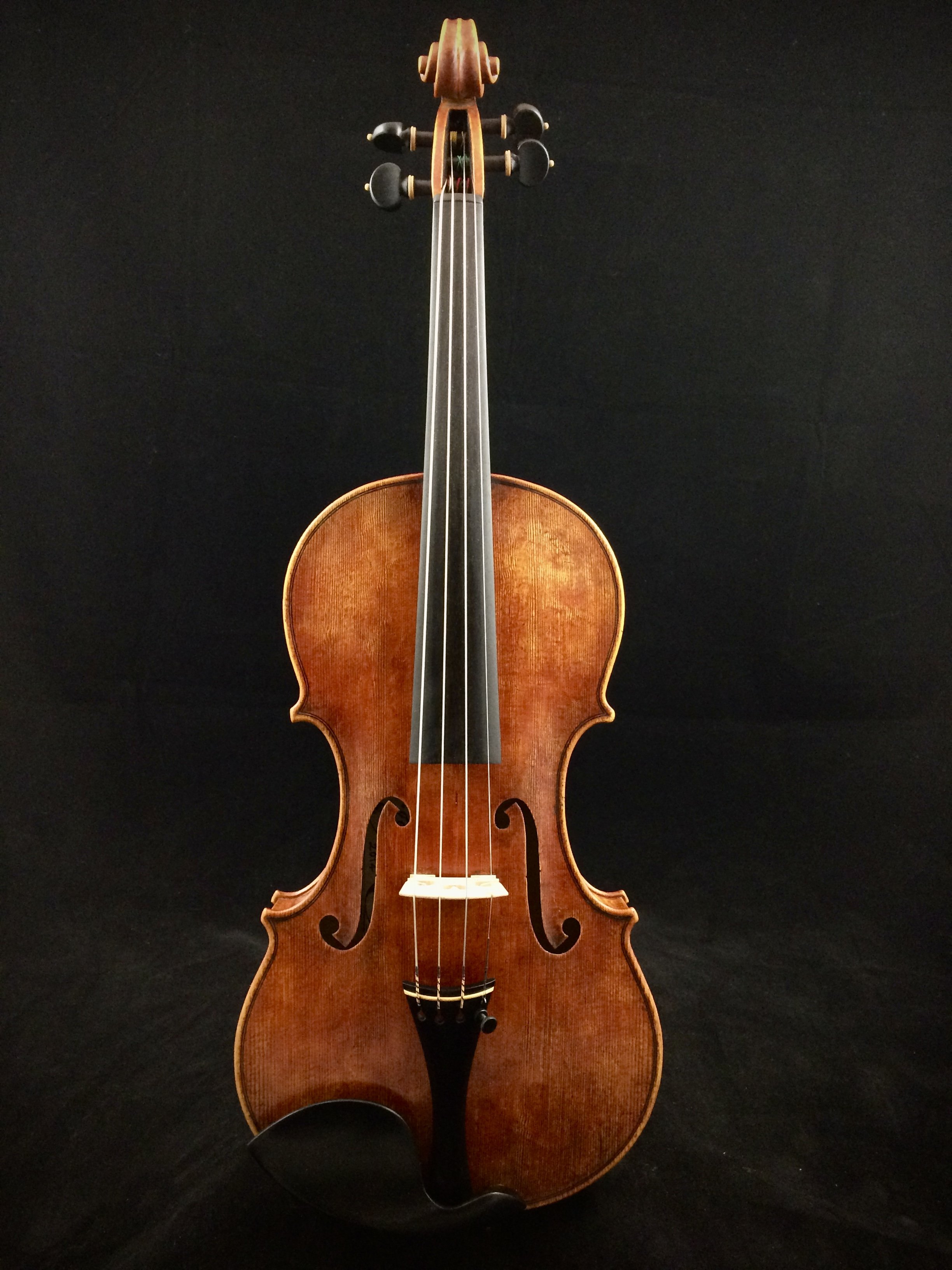 Giuseppe Guarerni del Gesù model violin on a black background with one fine tuner and Pirastro strings