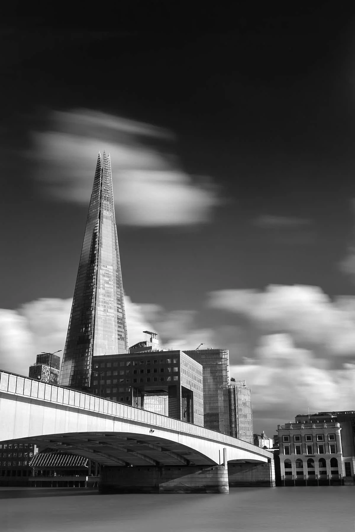 Long exposure black and white photograph of the Shard and London Bridge seen from the north side of the river Thames
