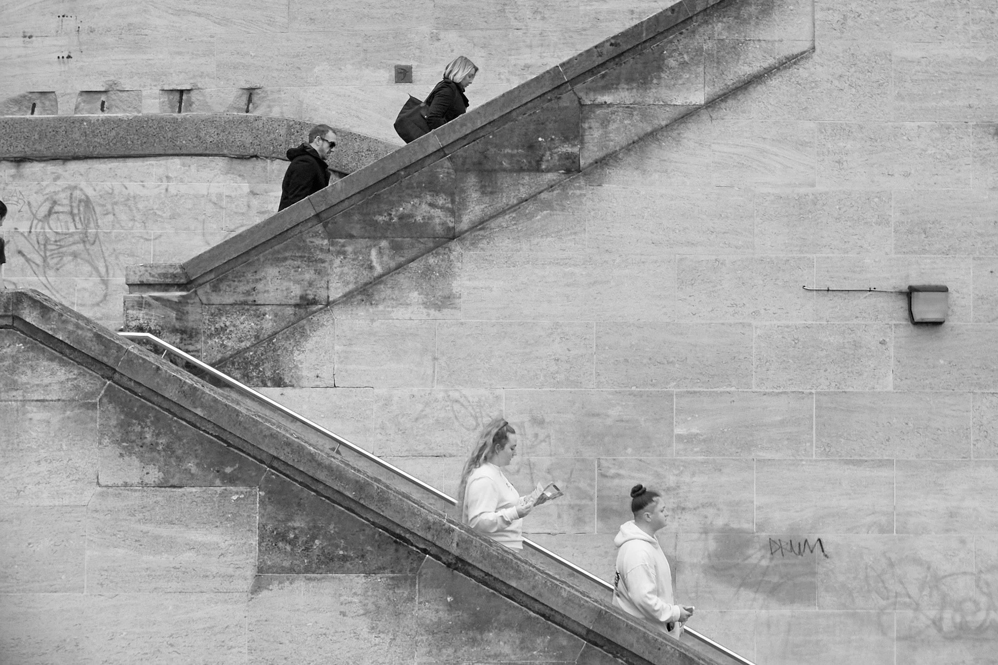 Four people walking down a concrete staircase in an urban setting.