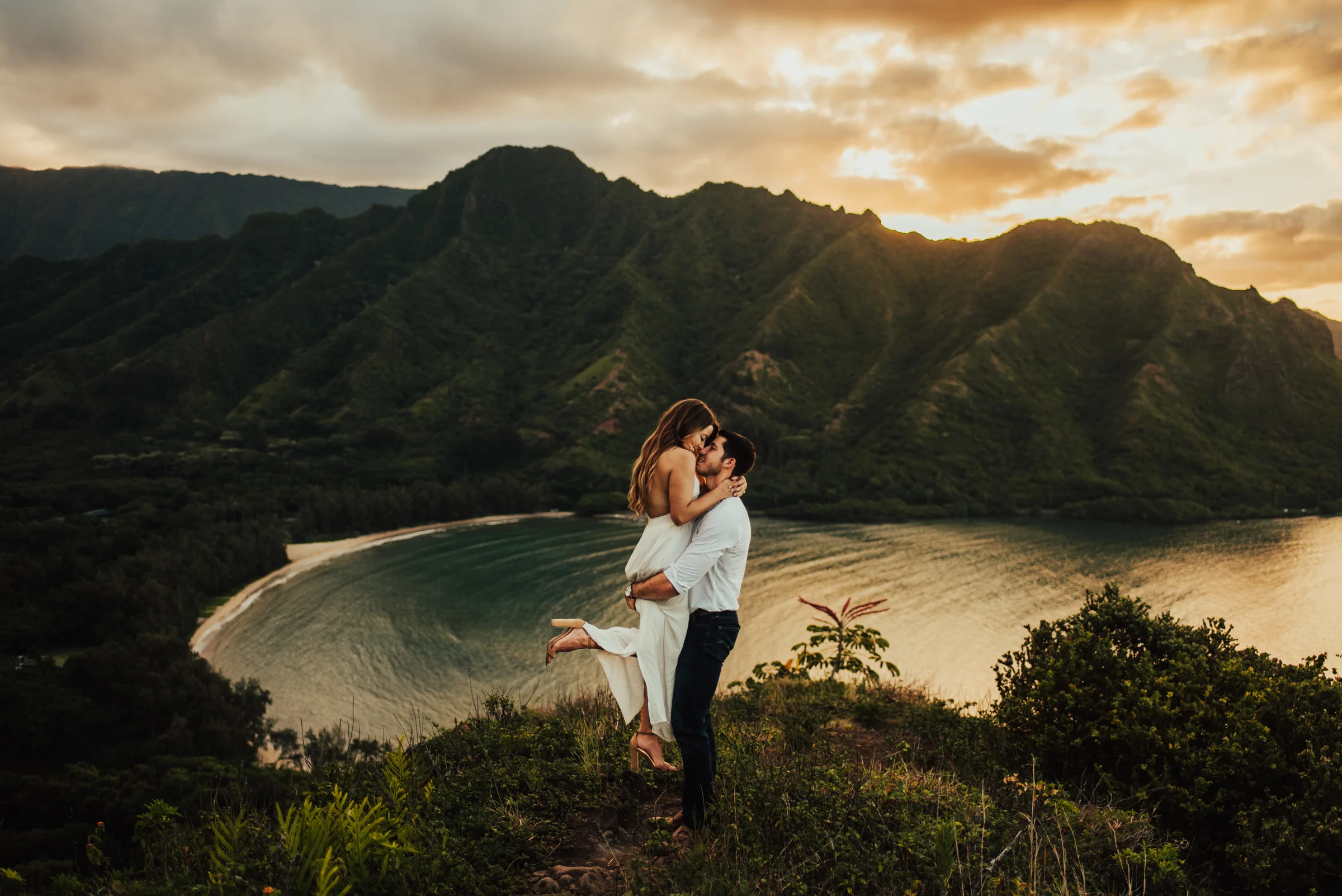 Hawaii cliffside portrait of groom lifting bride at sunset photographed by Big Sur Wedding Photographers Tessa Tadlock 