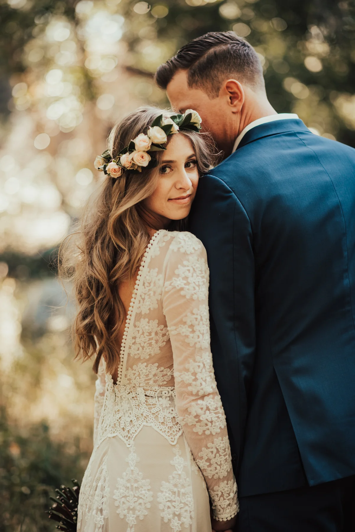 Bride with boho floral crown and long sleeve lace wedding gown holds hands with groom photographed by Big Sur Wedding Photographers Tessa Tadlock 