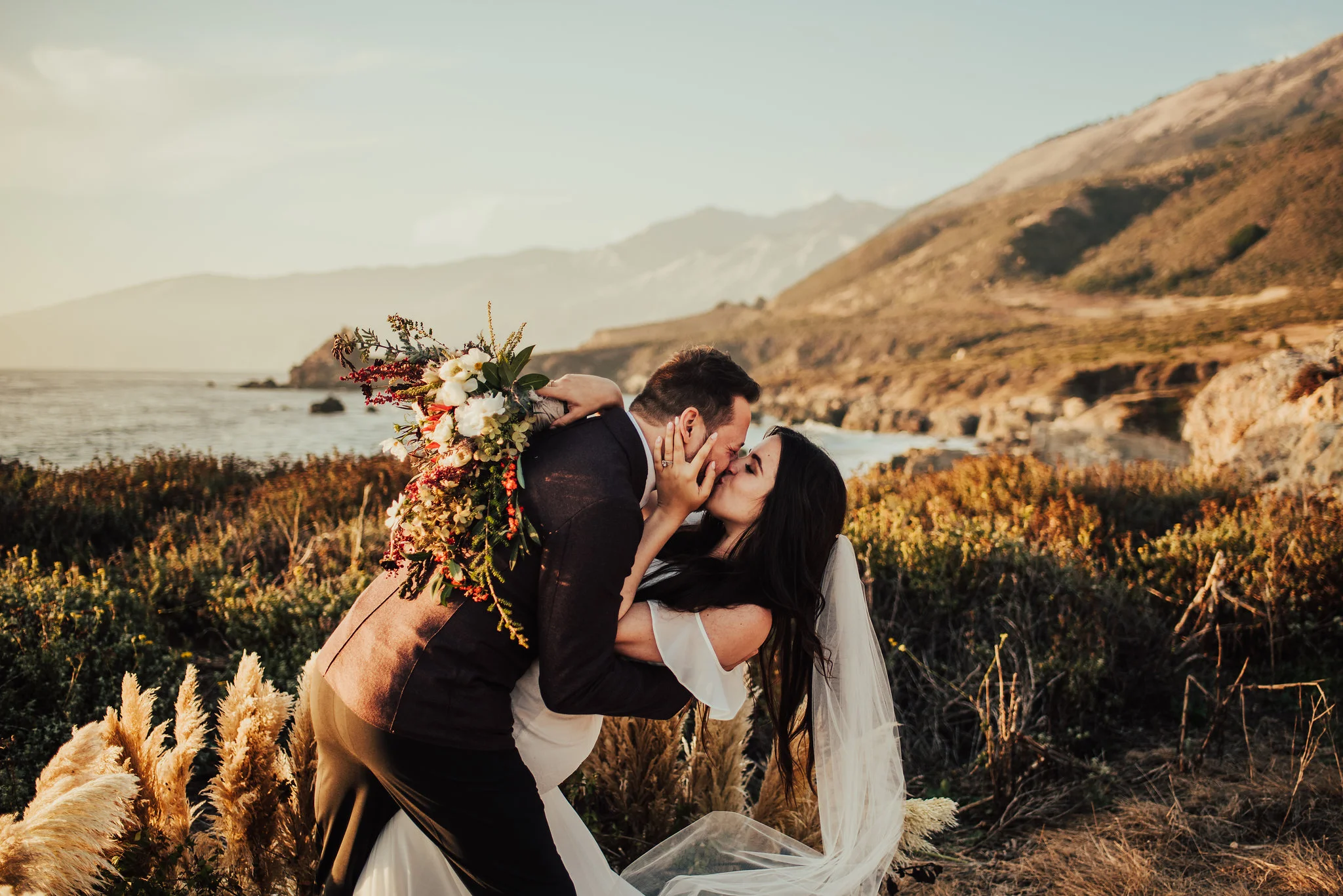 Groom dips bride for sweet first kiss by the ocean photographed by Big Sur Wedding Photographers Tessa Tadlock 