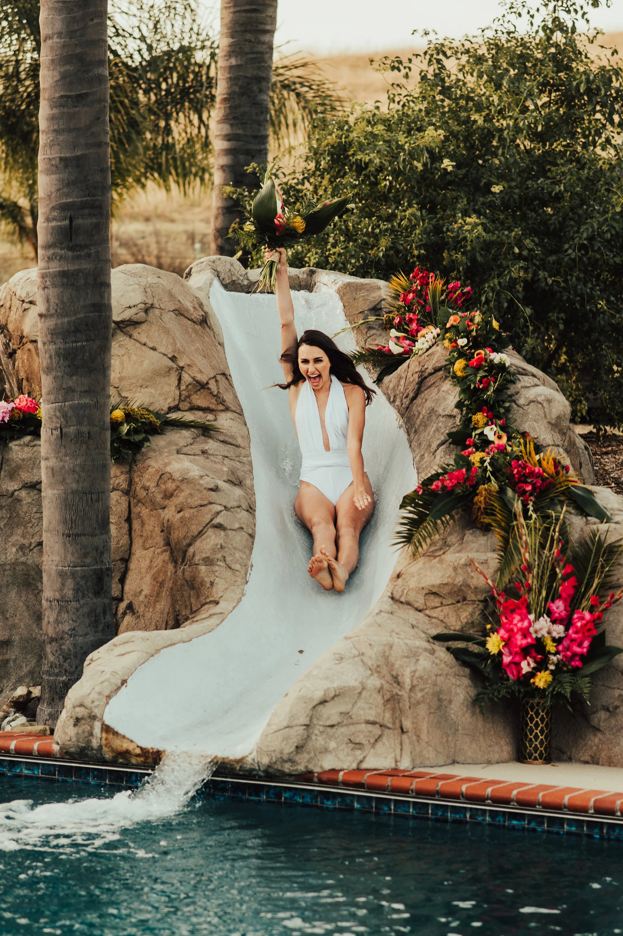 Free Spirited Bride waterslides at her swimming pool reception photographed by Big Sur Wedding Photographers Tessa Tadlock 
