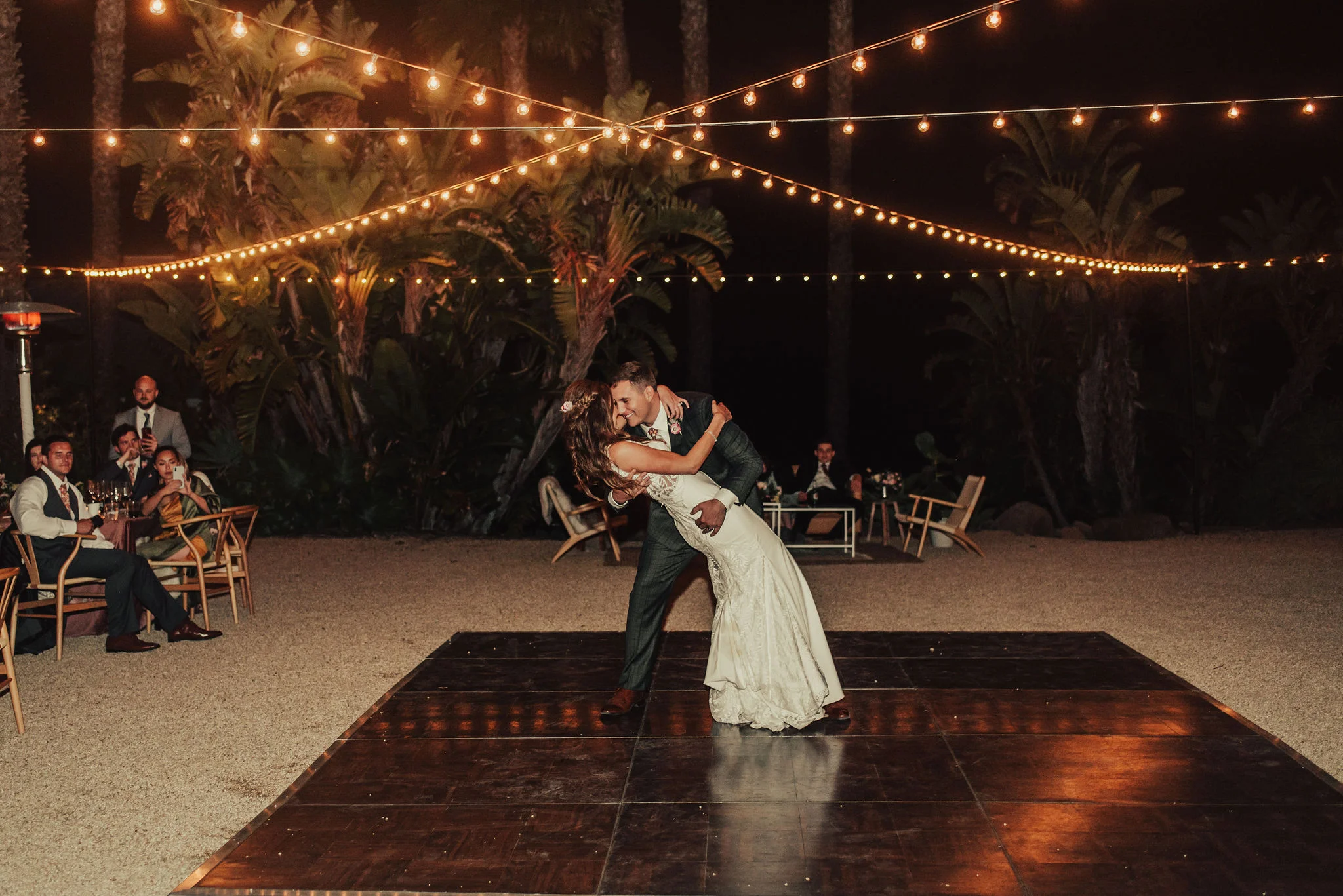 Groom Dipping Bride During First Dance Under String Lights Photographed by Big Sur Wedding Photographers Tessa Tadlock