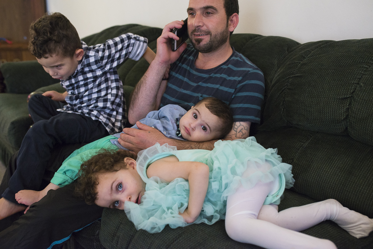 He calls and check with his family who are in Jordan as the children play around him.