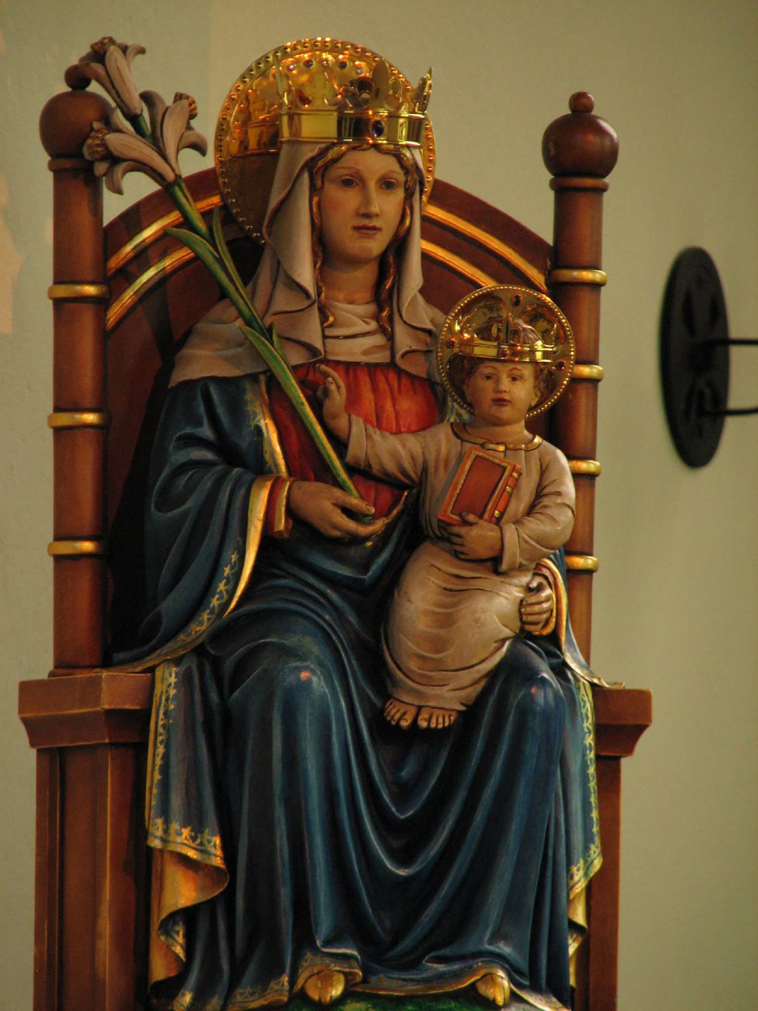 Photo: Our Lady, as she is venerated at Walsingham, is depicted as a simple woman, a mother. She is seated on the throne of Wisdom, in the midst of the Church which is represented by the two pillars symbolic of the Gate of Heaven, with seven rings to signify the seven sacraments and the seven gifts of the Holy Spirit.