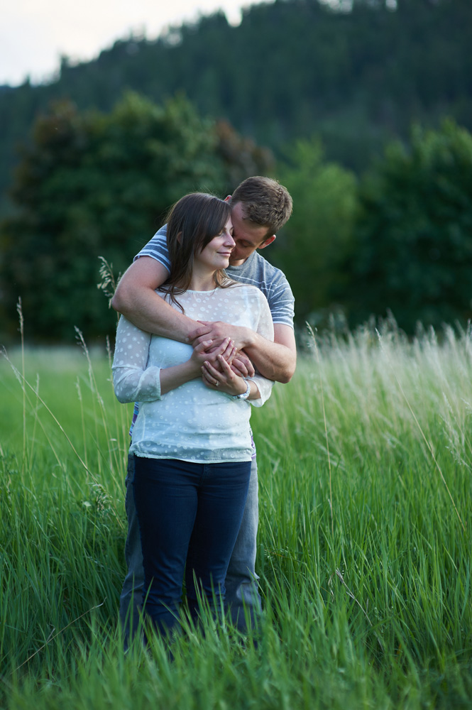 engaged-couple-embracing-in-a-grassy-field-at-sunset.jpg