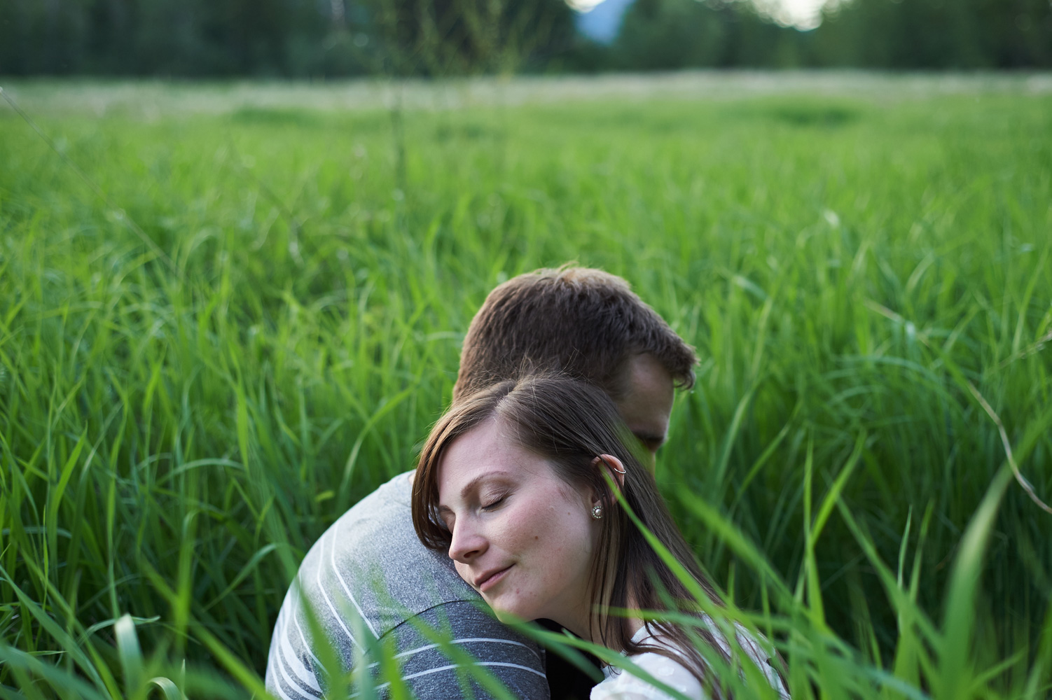 engaged-couple-in-a-grassy-field-hugging.jpg