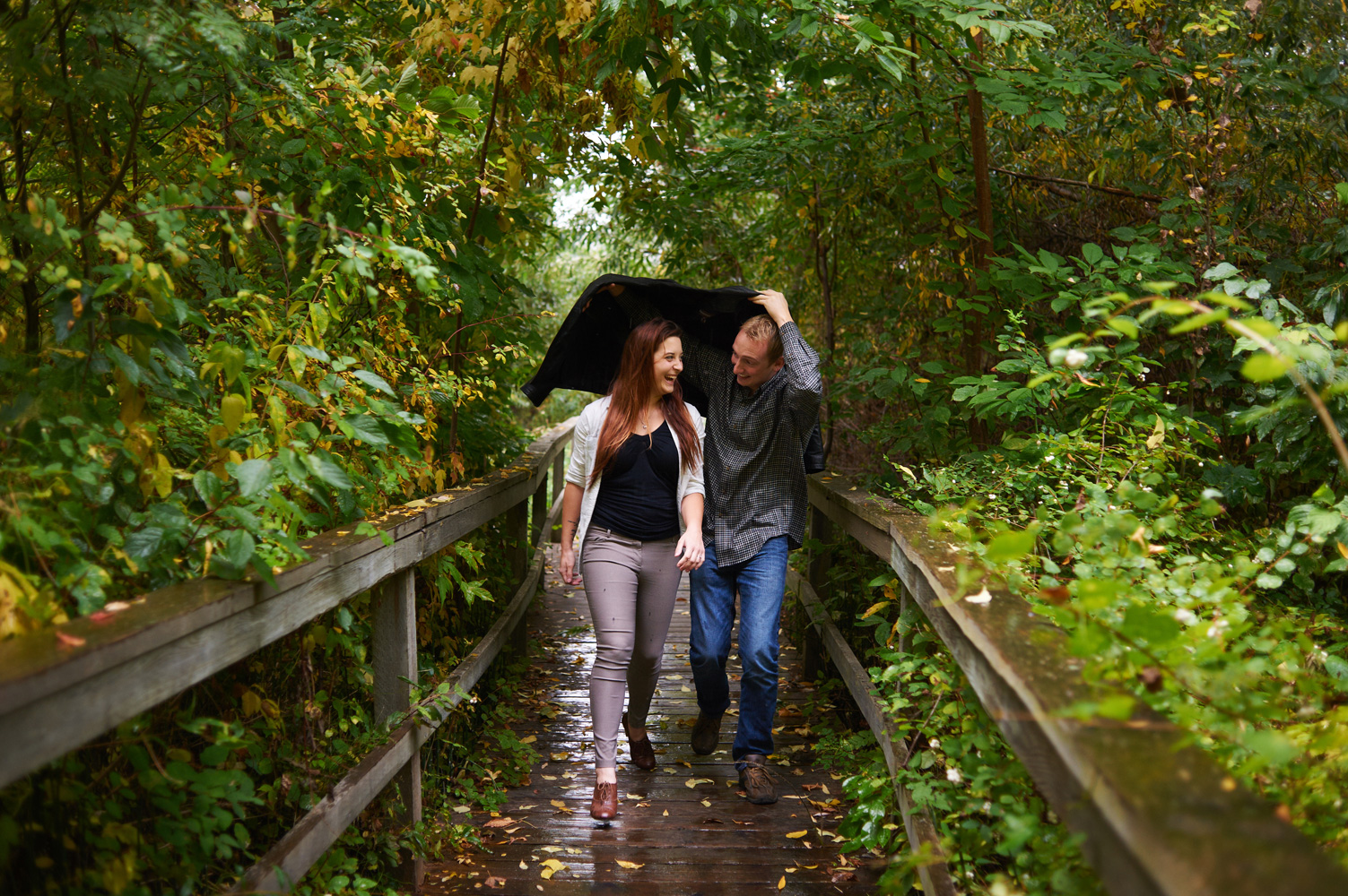 engaged-couple-running-in-the-rain-down-a-boardwalk.jpg