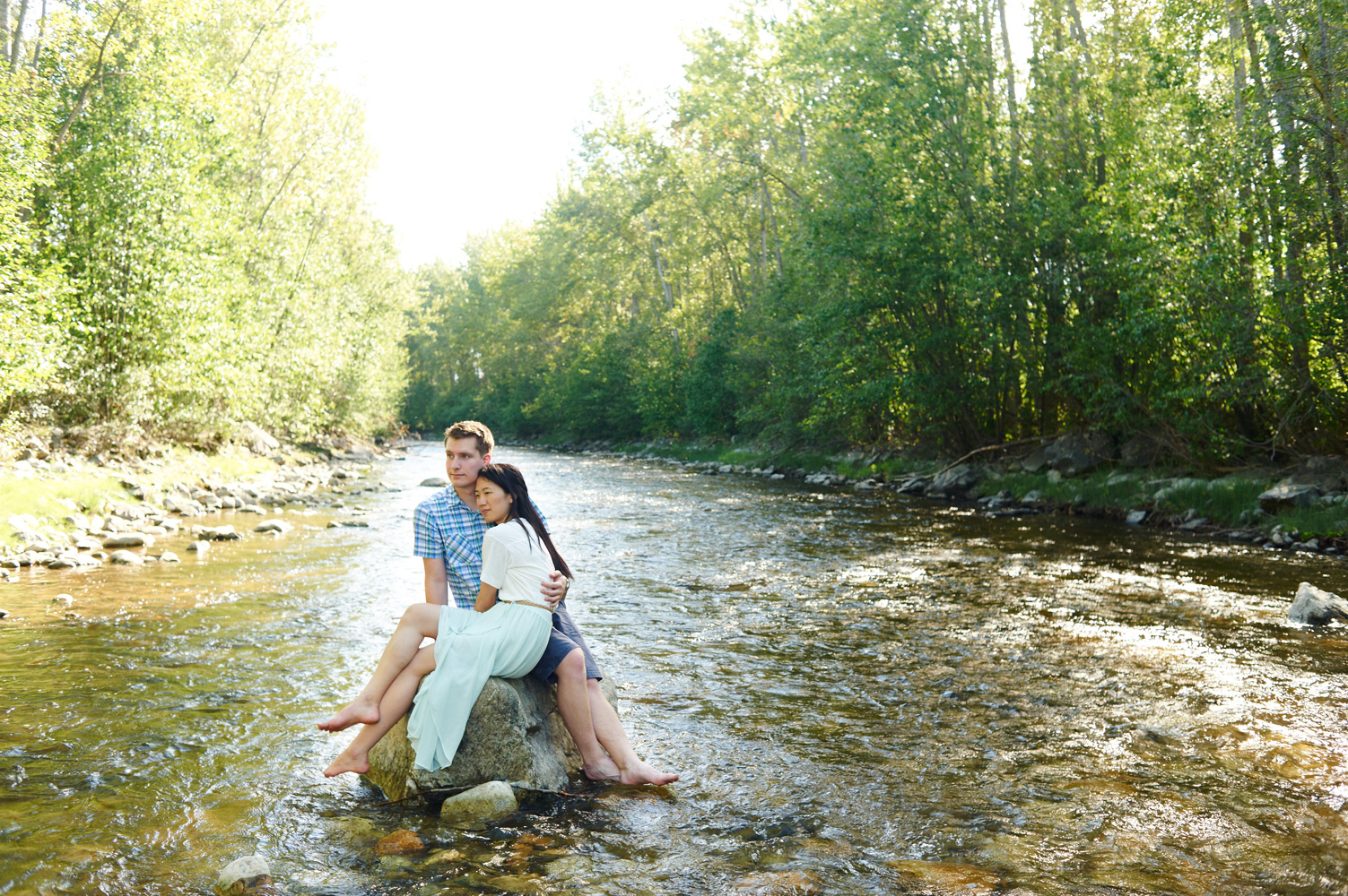 engaged-couple-sitting-on-a-rock-in-mission-creek-park-in-the-sun.jpg