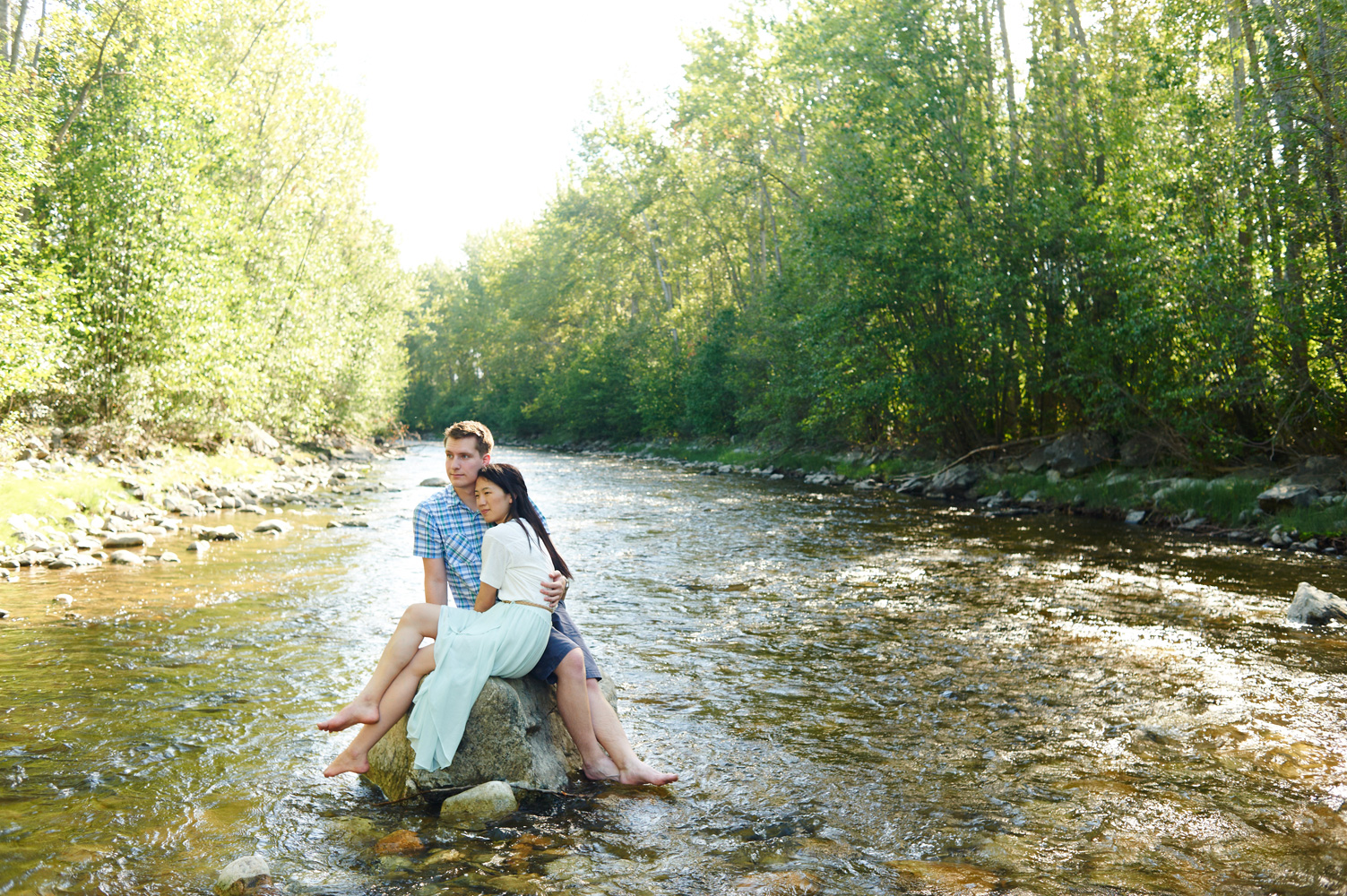 engaged-couple-sitting-on-a-rock-in-mission-creek-park-in-the-sun.jpg