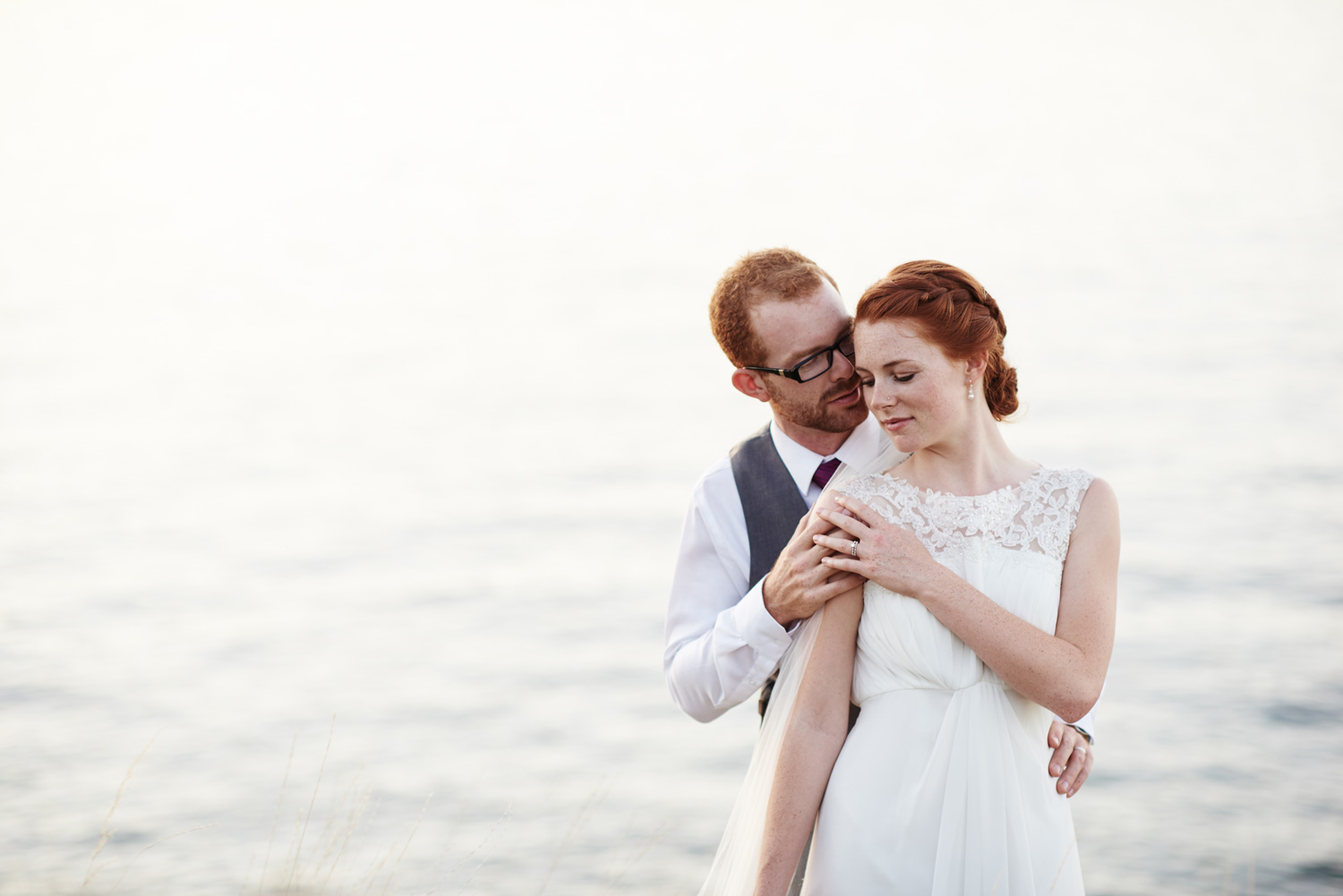 bride-and-groom-standing-by-the-lakes-edge-in-the-twilight.jpg