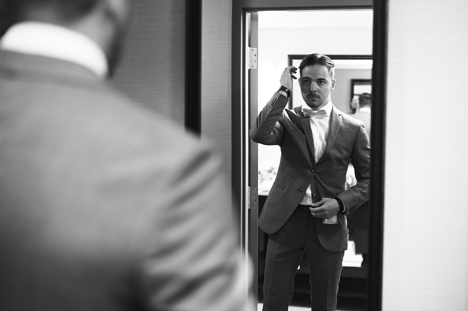 black-and-white-portrait-of-the-groom-looking-at-his-reflection.jpg