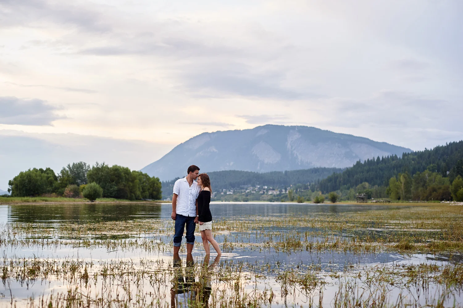engaged-couple-standing-in-water-in-evening-light-kamloops.jpg