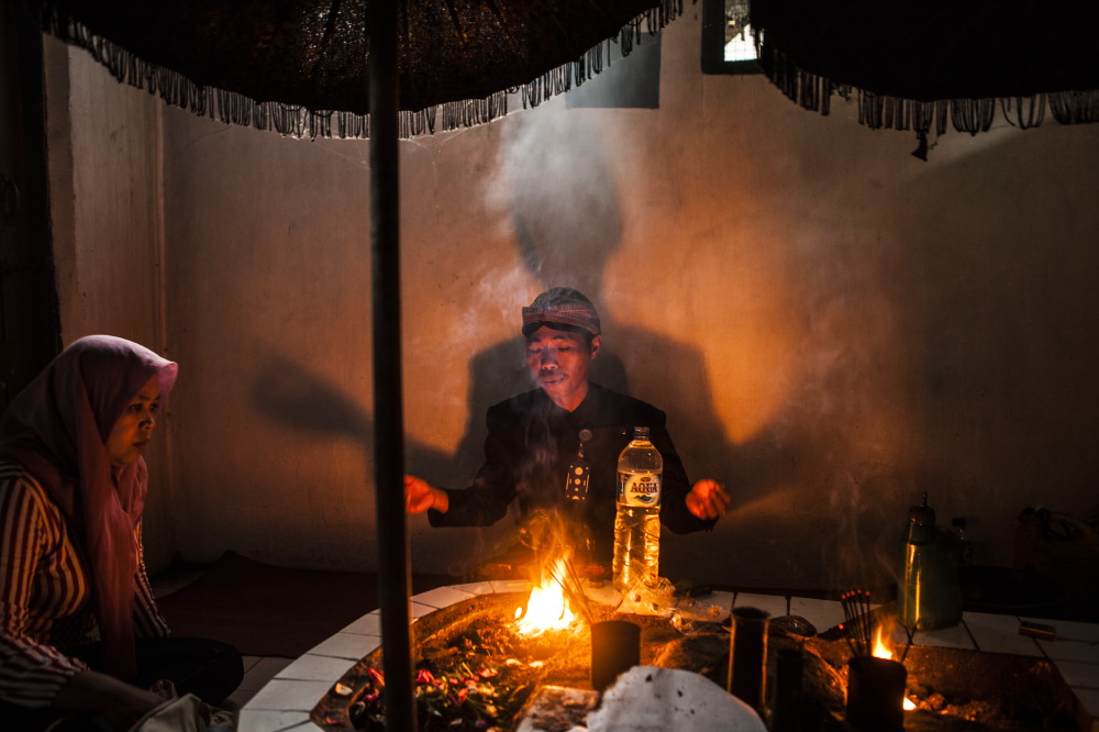 Shaman follower of Samudro's myth is blessing water for the pilgrims.