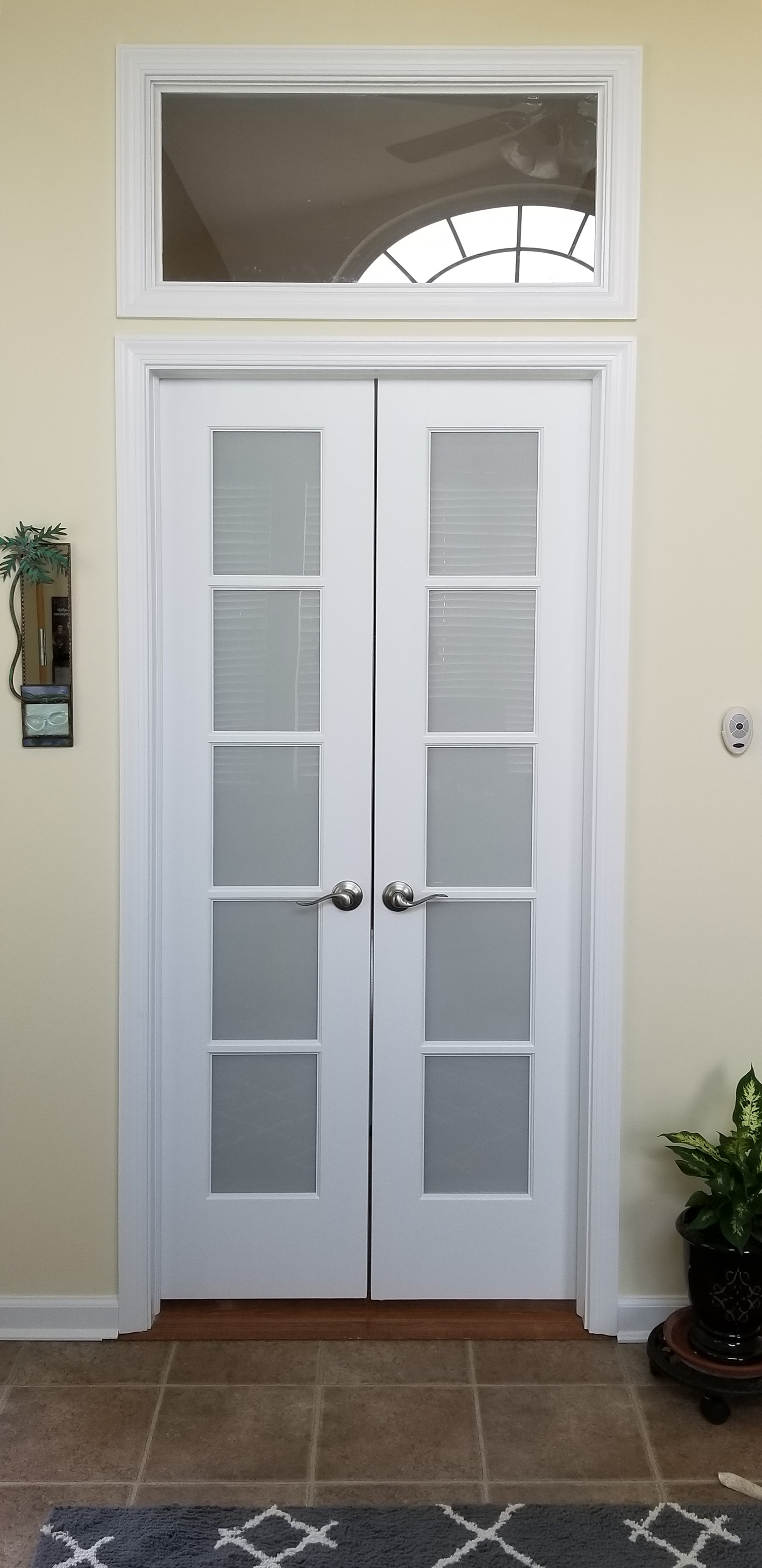 These french style double doors have ball catches at the top and a transom custom window above.