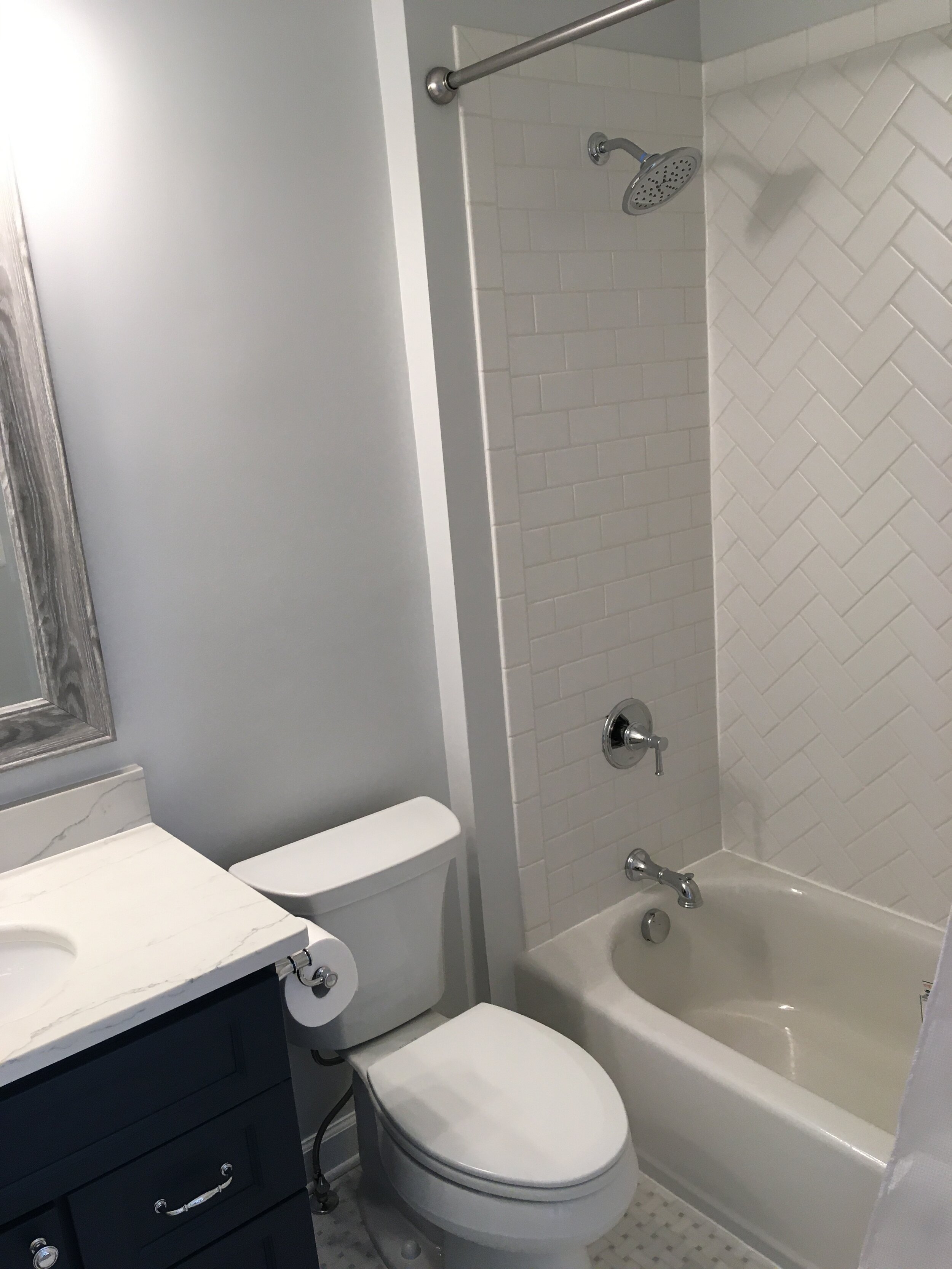  This finish bathroom has white tile installed in a herringbone design over a new American Standard white tub. The floor is Altuve Glacier white basket weave with ice grey dots. A Wolf vanity cabinet with the Dartmouth door style was also added, incl