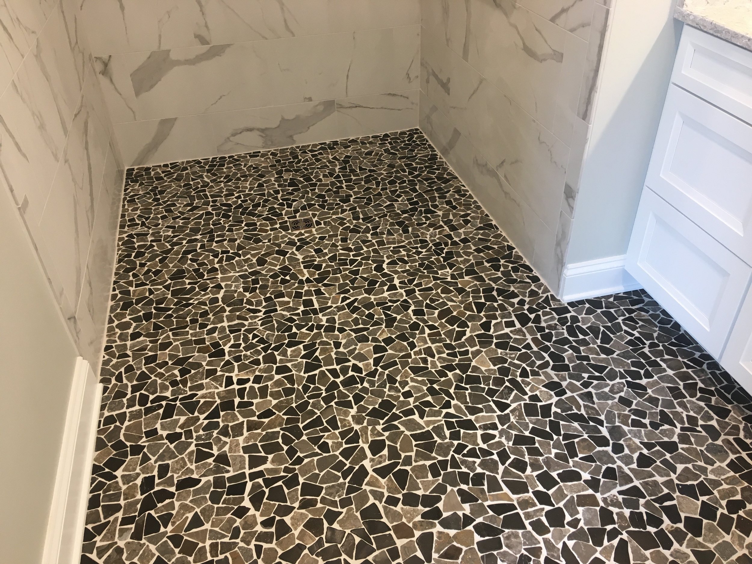  Recently completed bathroom with no threshold, with a ‘River Rock’ tile floor and 12 by 24 inch wall tile. 