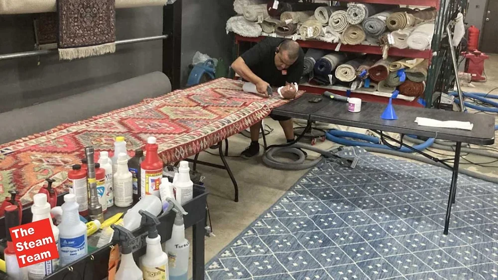 Technician repairing a patterned rug in a workshop, representing area rug cleaning in Austin.