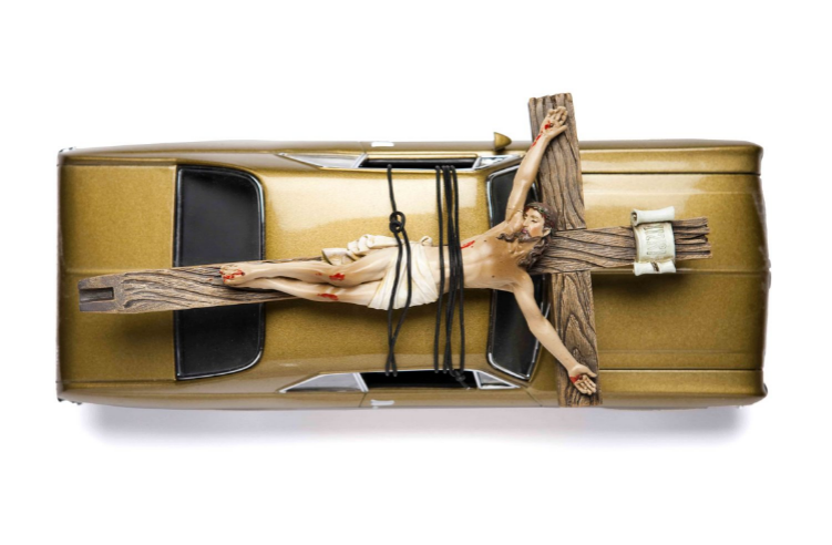 Road Kill 2008 Car and crucifix This sculpture depicts a crucified Jesus Christ strapped to the top of an American muscle car. It should remind the viewer of cliché images of a hunter’s freshly killed deer tied to the roof of the car. The mix of American —muscle cars with an iconic religious image— presents the artist’s critical portrait of some people's notions of middle America.