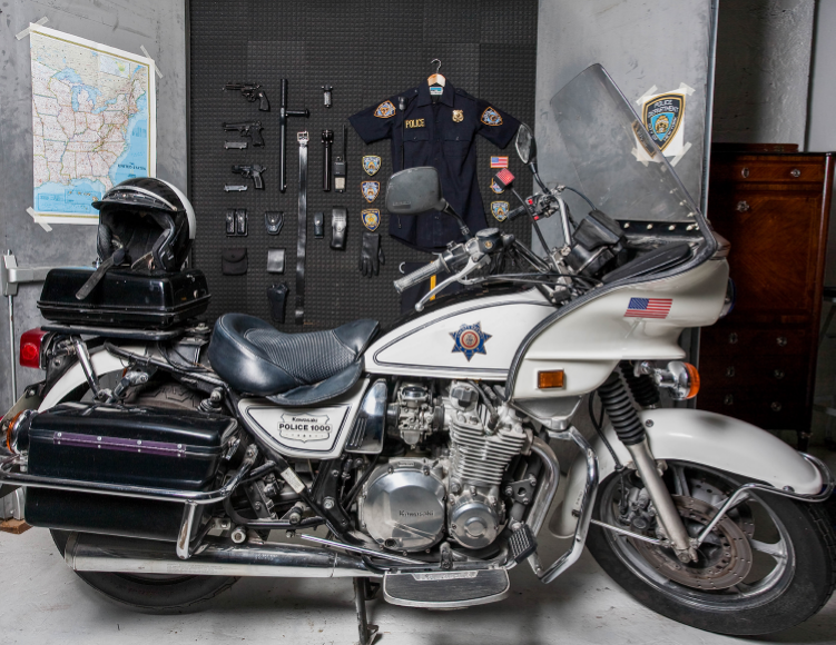 2009 Found police objects, motorcycle, wood and acoustic panels Sebastian ErraZuriz searched for and purchased the elements that comprise a complete United States police uniform on various internet sites for almost two years. The collected objects, tools, badges, and weapons allegedly came from former policemen and other ex-law enforcement professionals who had retired and sold their belongings online. Once the artist finally completed the full collection, it was displayed like a movie arsenal behind a couple of secret doors installed in his studio. The art installation calls to mind the secret rooms in which superheroes hide their identities or sociopaths plan their robberies. For the artist, this installation highlights how easily a common citizen can legally acquire a full policeman's uniform, allowing that person maximum authority and power on the streets. 