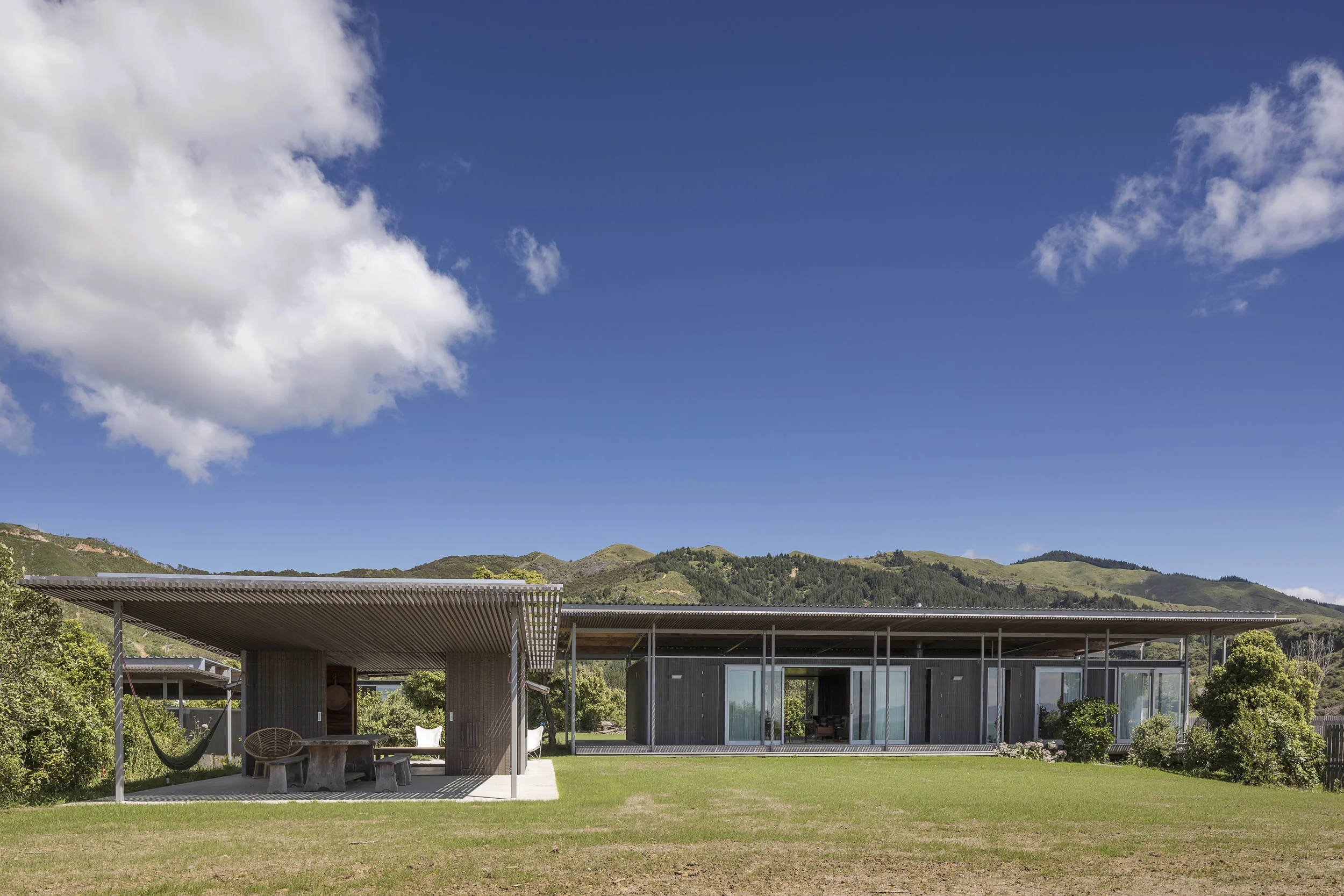 The post-cyclone additions to Bach with 2 roofs re-finish the buildings to the new clearing, but do so by understanding a landscape that continues to shift, and a native forest that in time will again conceal and shelter. Image: Irving Smith Architects