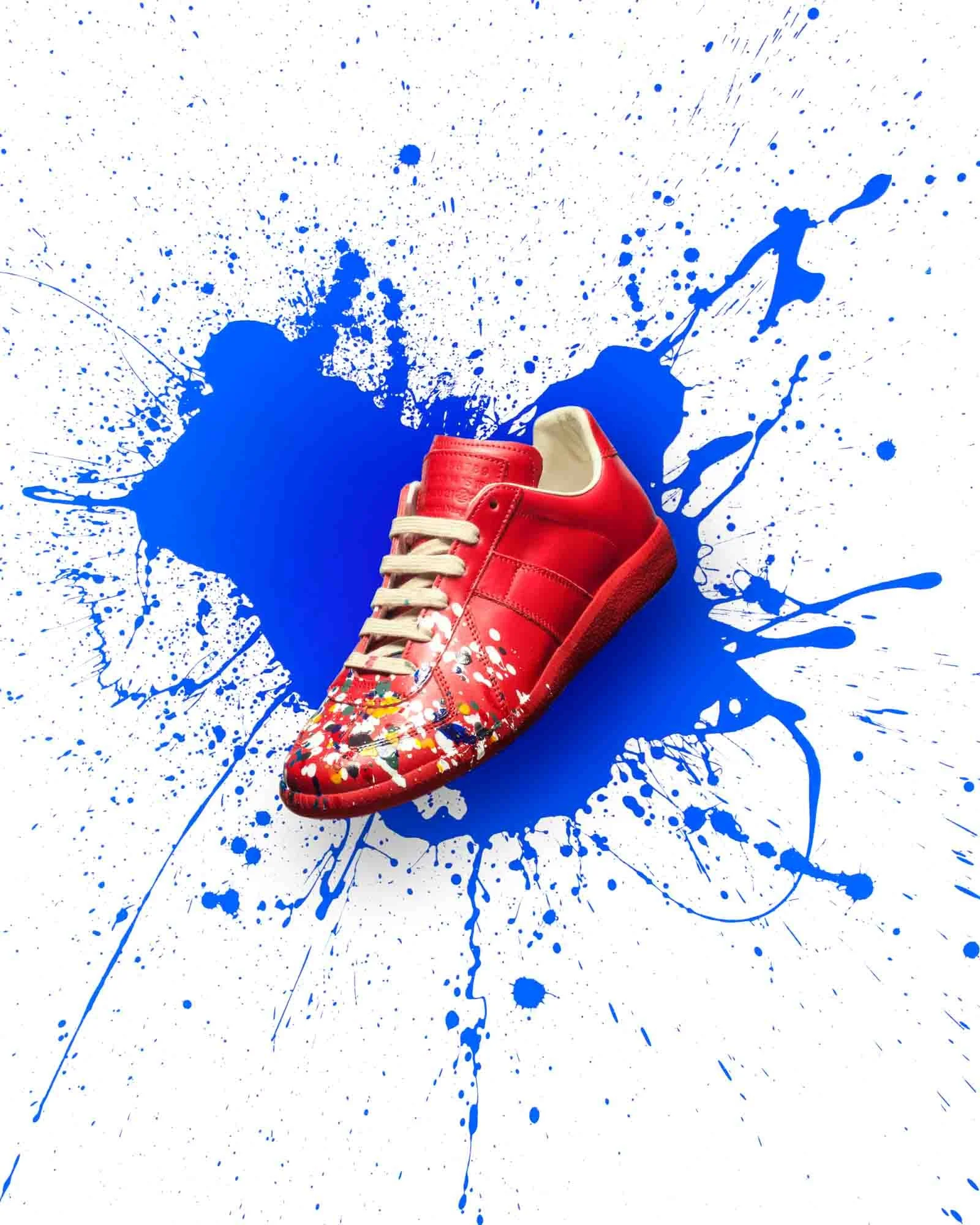 Red sneaker on a splattered blue paint background photographed by Boston product photographer Adam DeTour