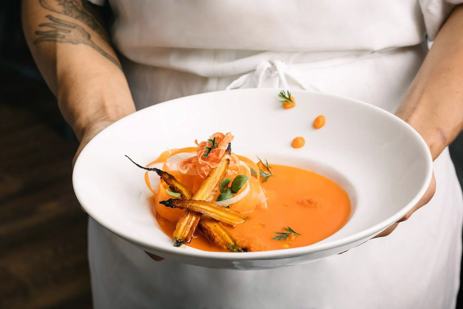 Bowl of carrot soup being held by chef at Boston Restaurant by food photographer Adam DeTour