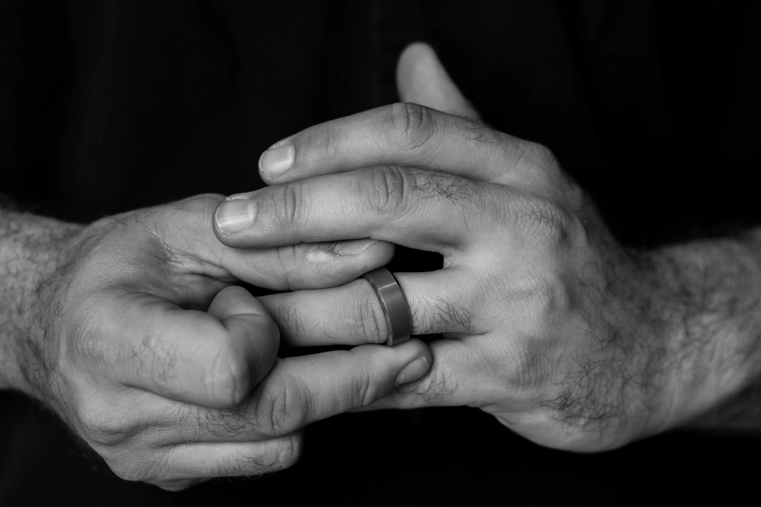 Black &amp; white closeul of person’s hands as they play with their wedding ring. This image represents marriage, child custody, and dissolution litigation.