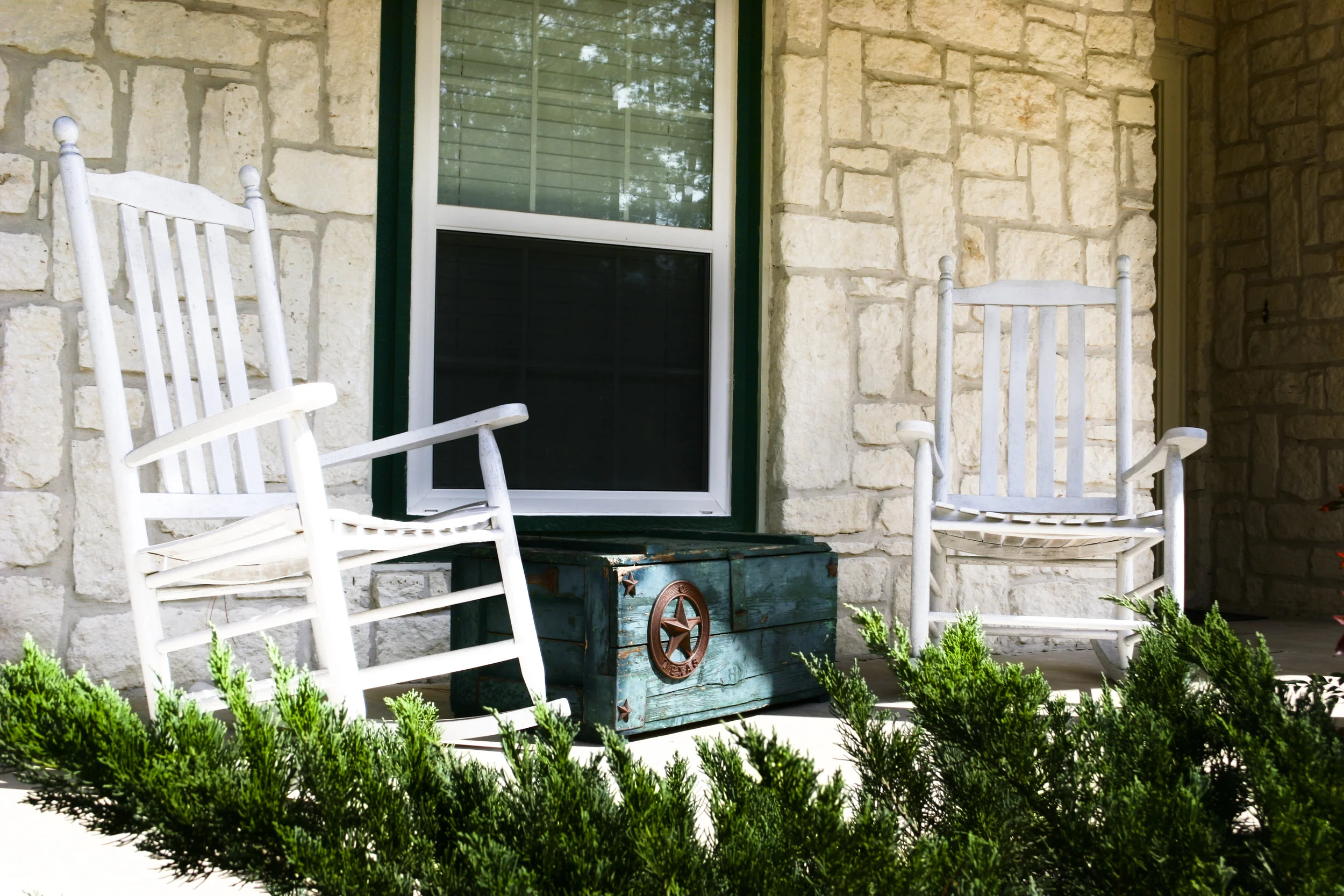 A stone house with two rocking chairs sitting on the porch.