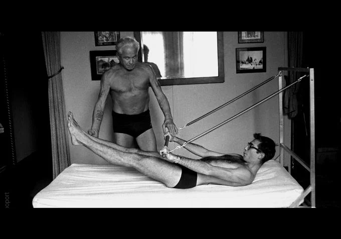 Joseph pilates instructing student on apparatus