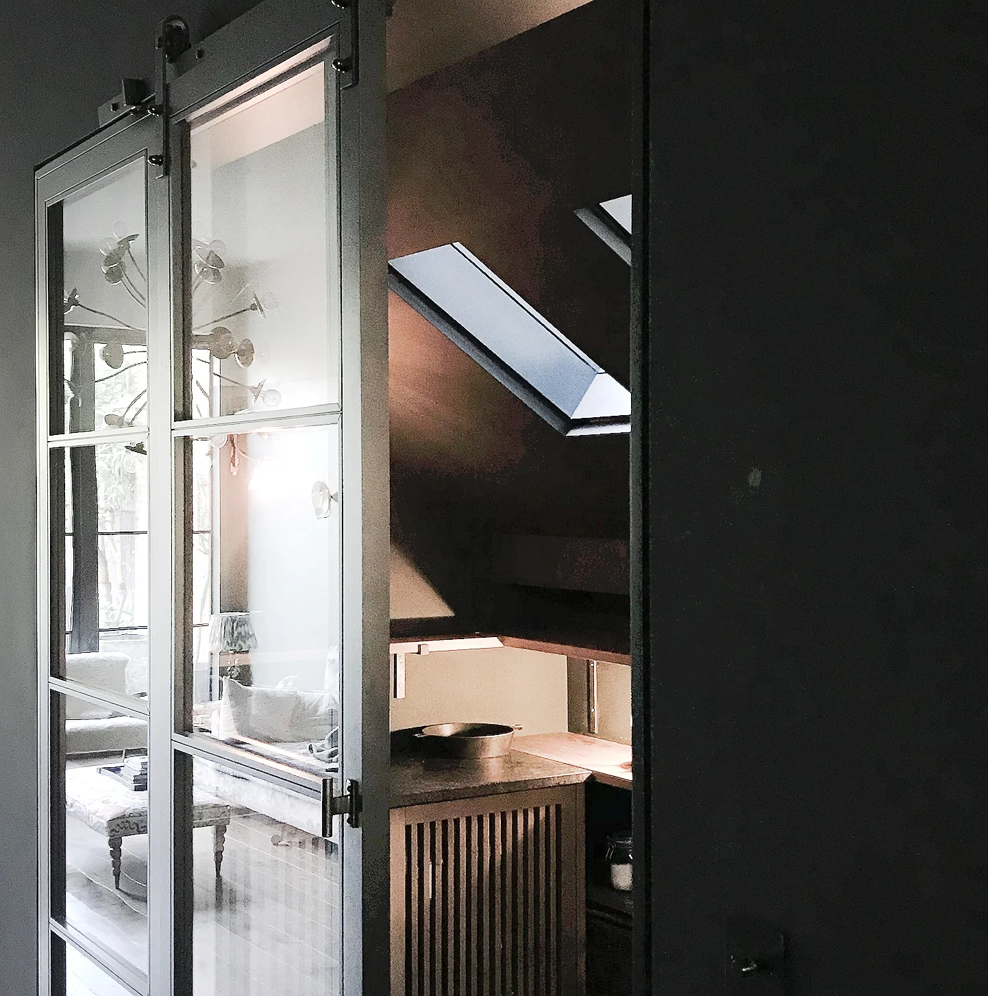 Black pantry, with sliding black wood and glass barn door, oak and steel cabinetry and shelving